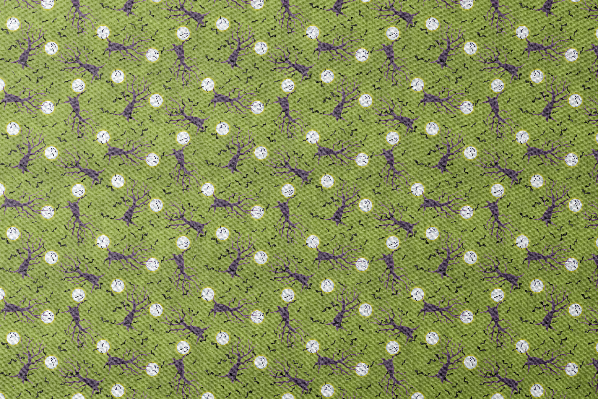 Halloween fabric design with purple haunted trees, bats, and glowing moons on a green background, illustrated by Nicole Tamarin. designs flat mockup