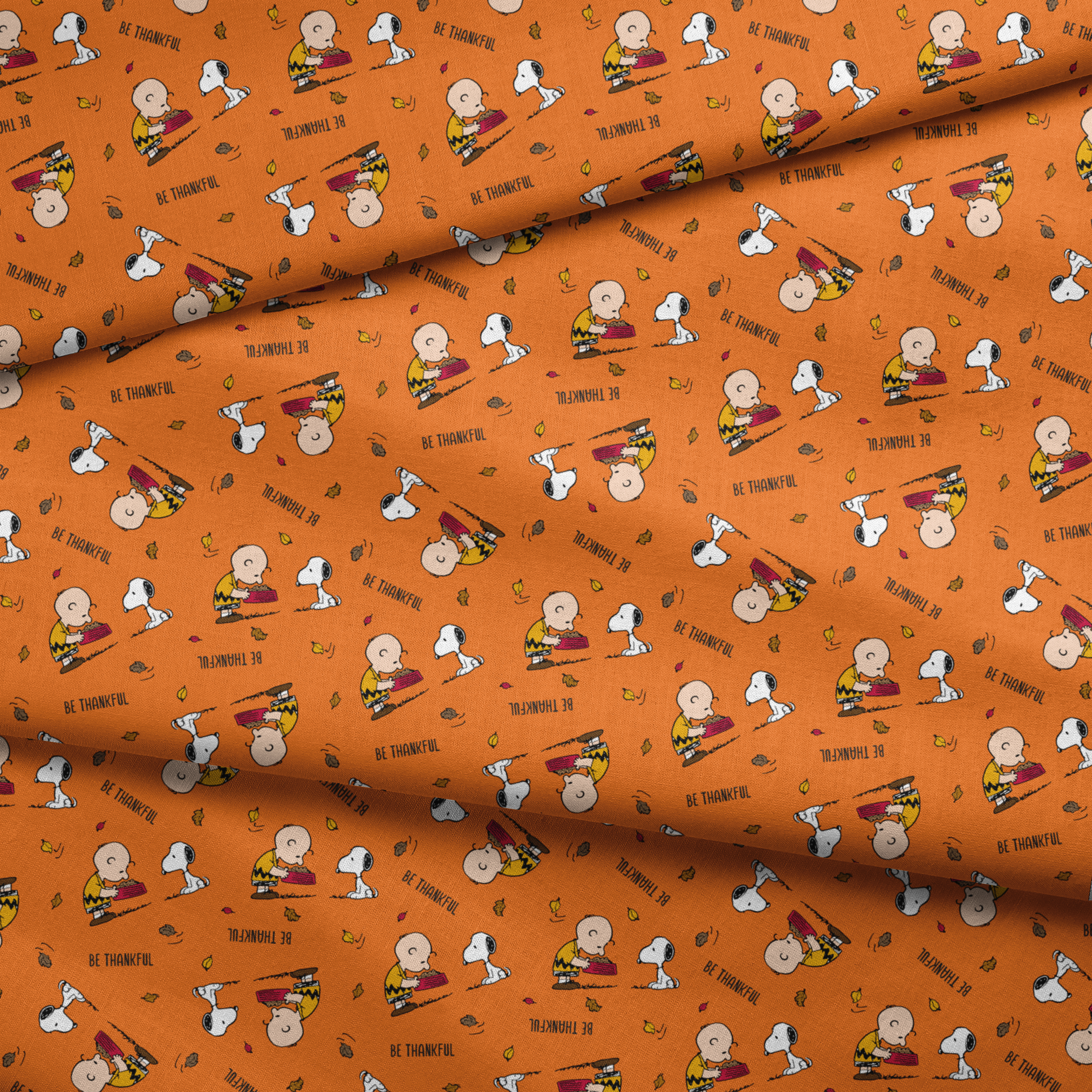 Peanuts characters on orange background with autumn leaves and "Be Thankful" text pattern fabric fold mockup