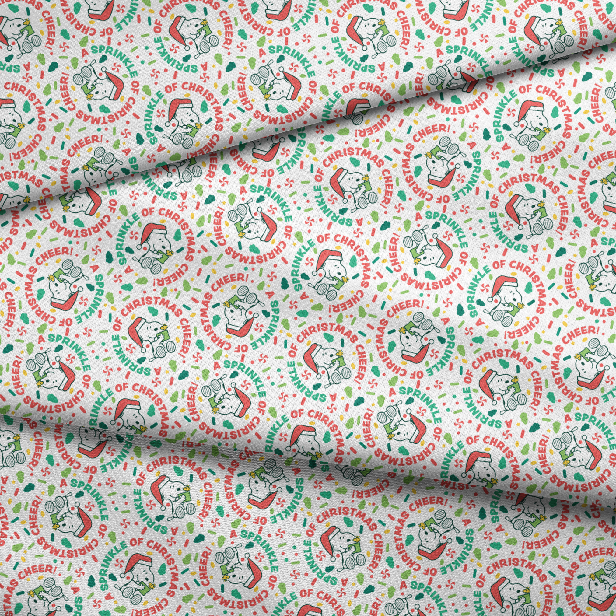 Holiday pattern with Snoopy wearing Santa hat, surrounded by "Merry Christmas", "Cheer", and candy designs on white background fabric fold mockup