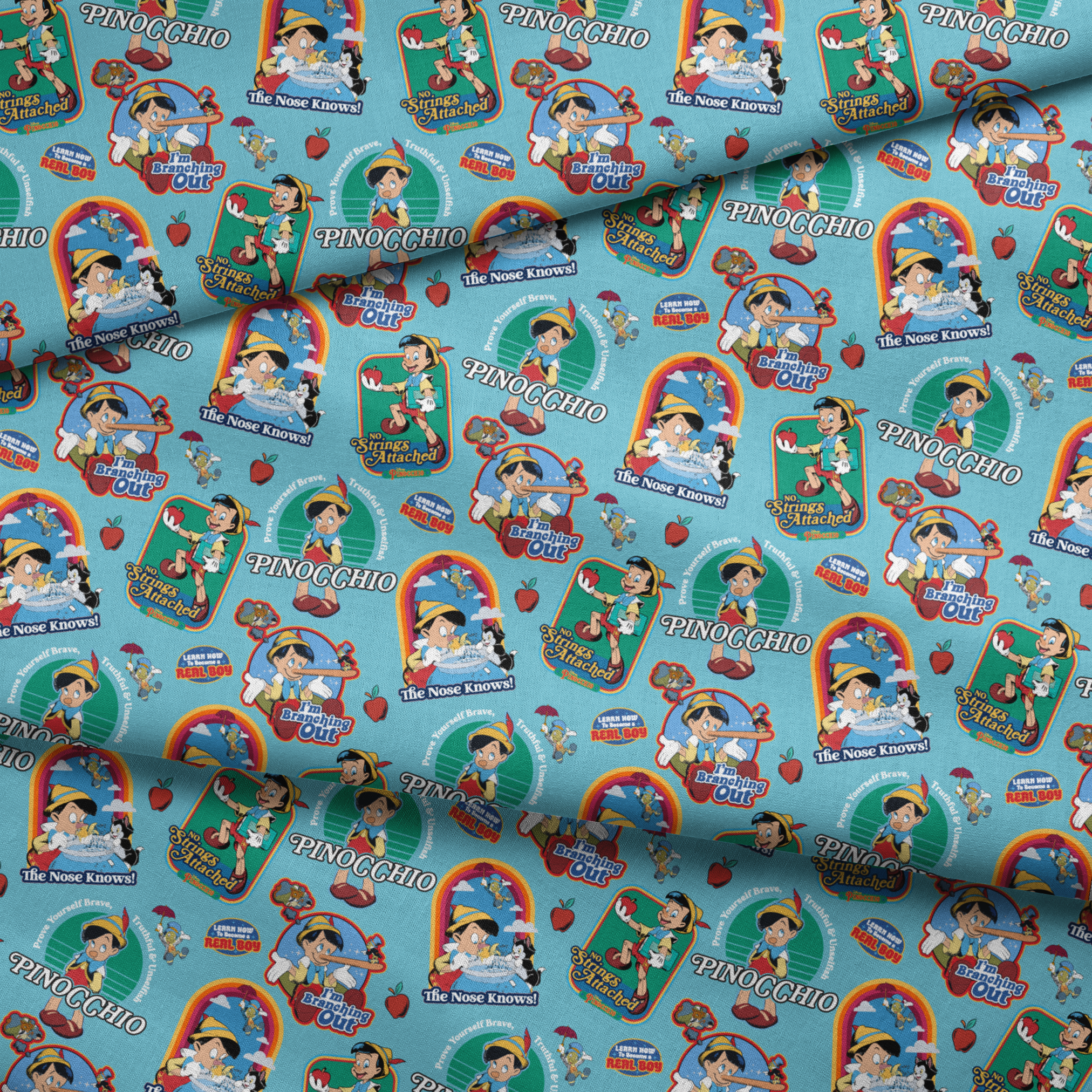 Colorful Pinocchio cartoon pattern featuring puppet characters, slogans, and red apples on teal background fabric fold mockup