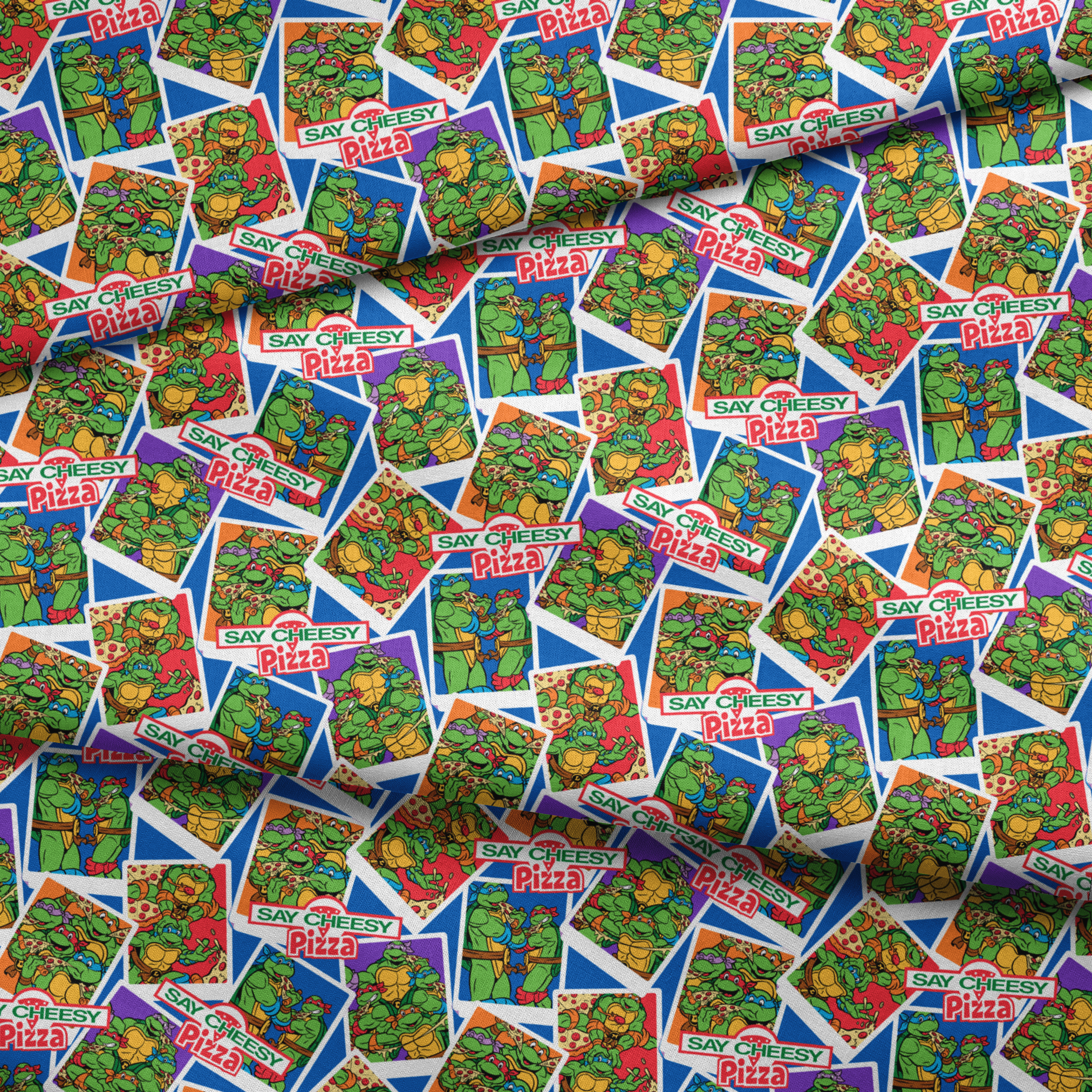 Colorful collage of Teenage Mutant Ninja Turtles cartoon characters with "Say Cheesy Pizza" text on vibrant background fabric fold mockup