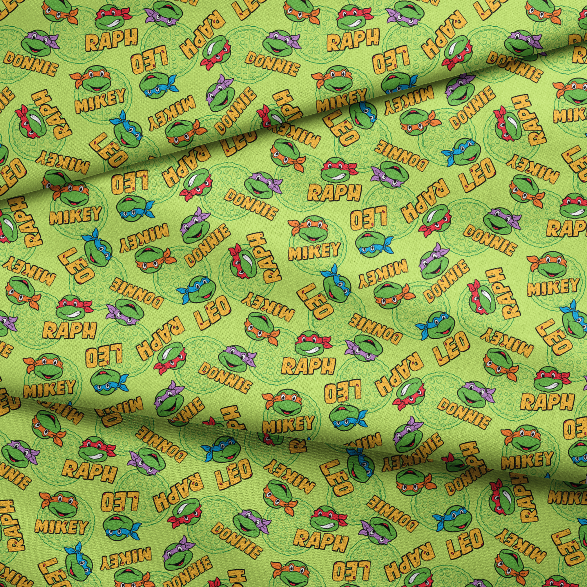 Teenage Mutant Ninja Turtles pattern with cartoon faces, names, and colorful masks on green background fabric fold mockup