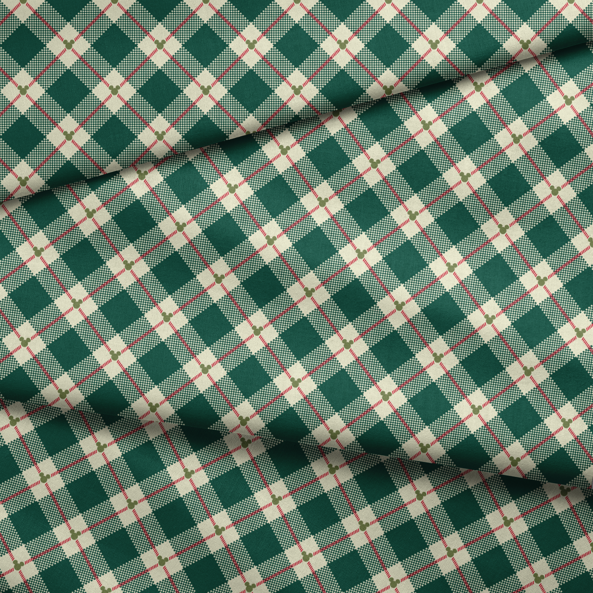 Diagonal green and cream plaid pattern with small Mickey Mouse silhouettes at intersections of red stripes fabric fold mockup