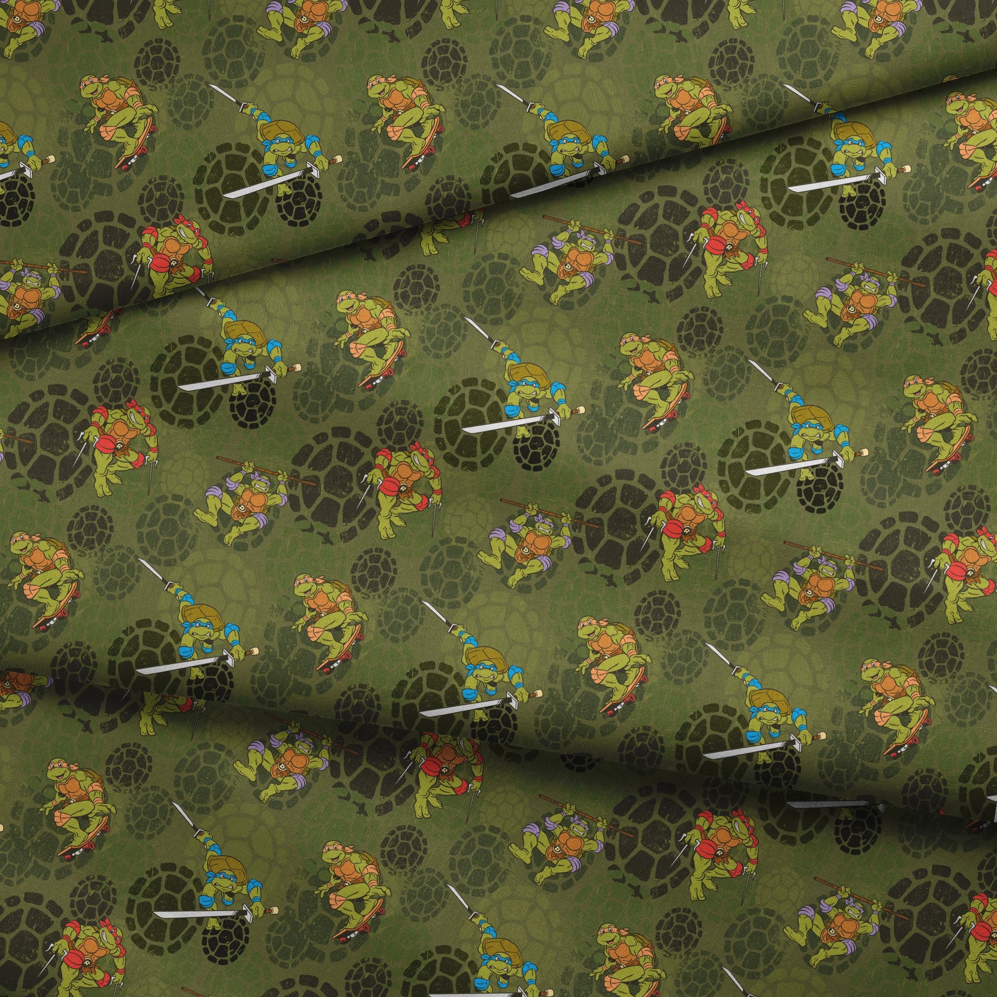 Teenage Mutant Ninja Turtles characters in action poses on green background with turtle shell patterns fabric fold mockup