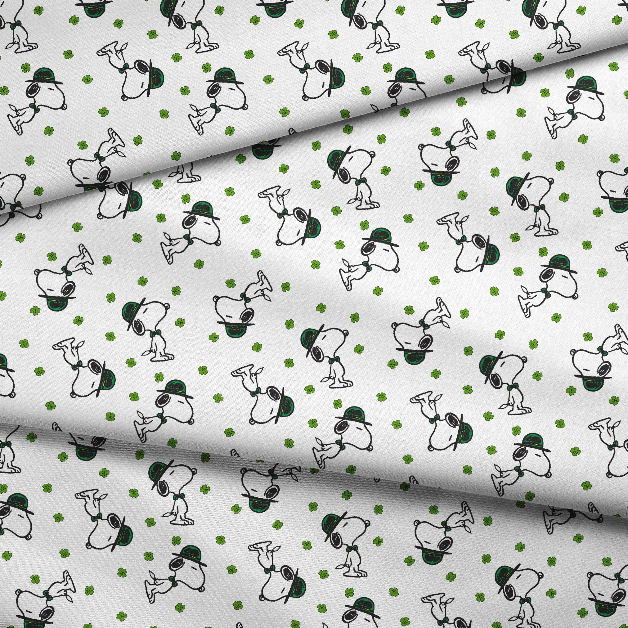 Cartoon Snoopy wearing green hat with shamrocks scattered across white background fabric fold mockup