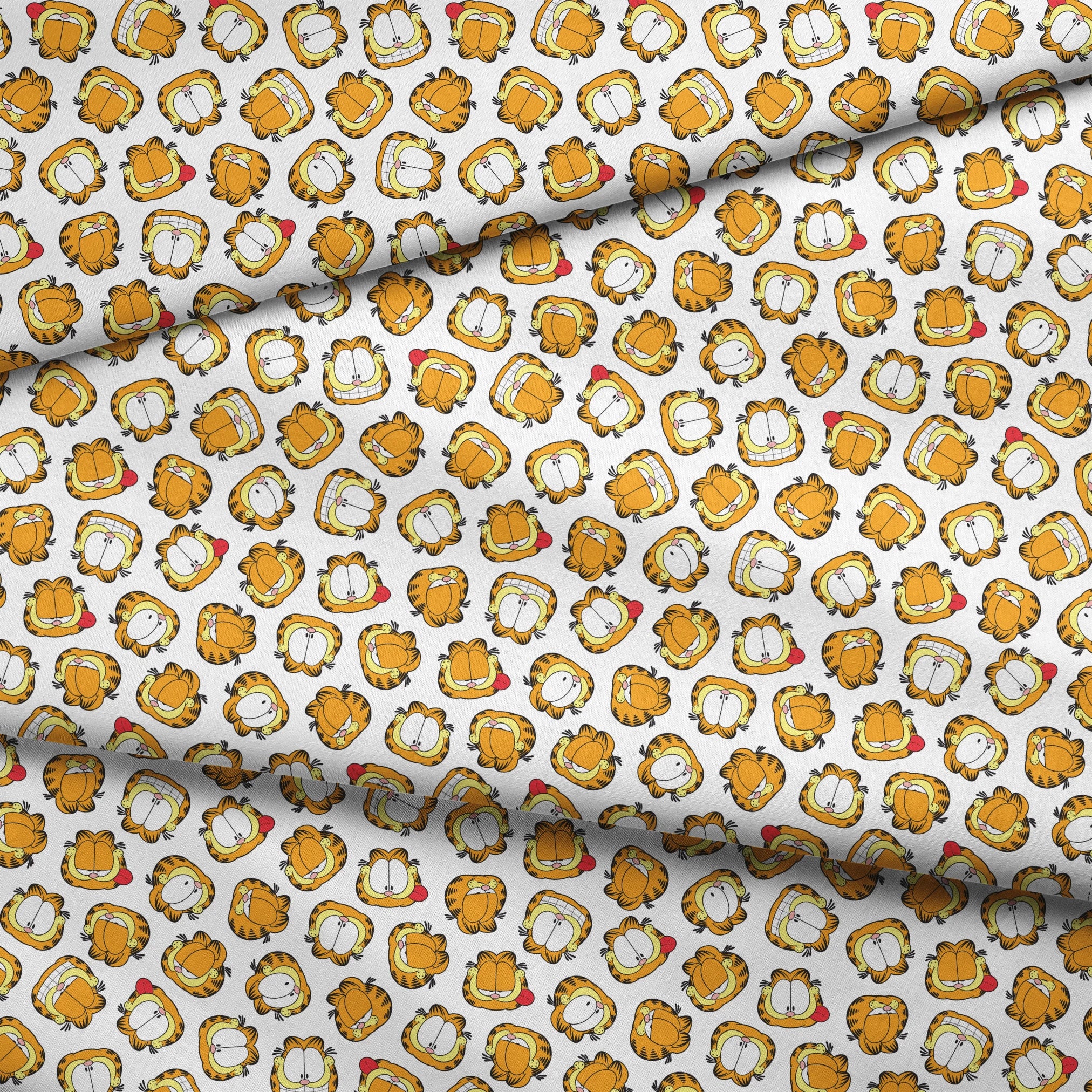 Pattern of cartoon cat faces with orange and yellow coloring against white background fabric fold mockup