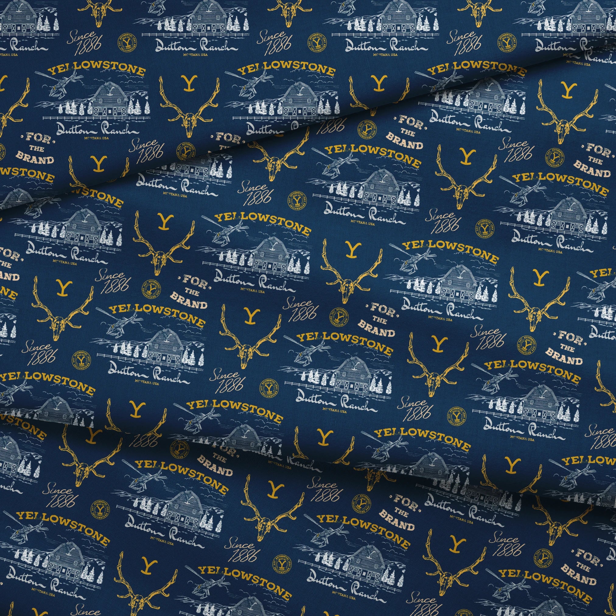 Yellowstone-themed pattern with Dutton Ranch logos, deer antlers, and "Y" branding on navy blue background fabric fold mockup