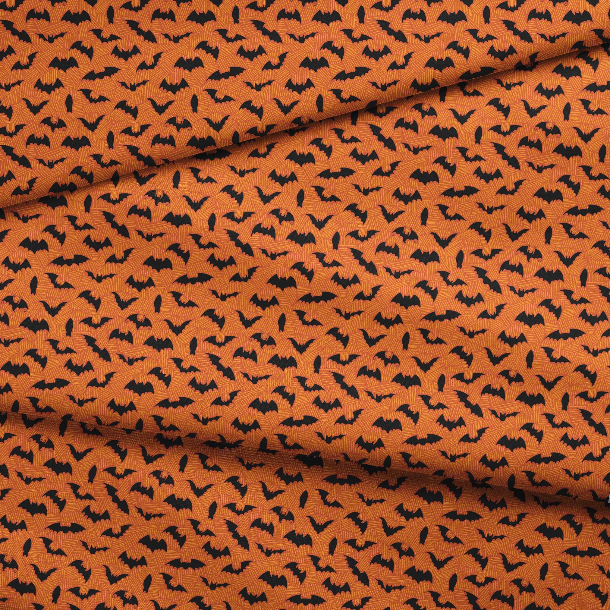 Halloween pattern with black bats scattered across an orange textured background fabric fold mockup
