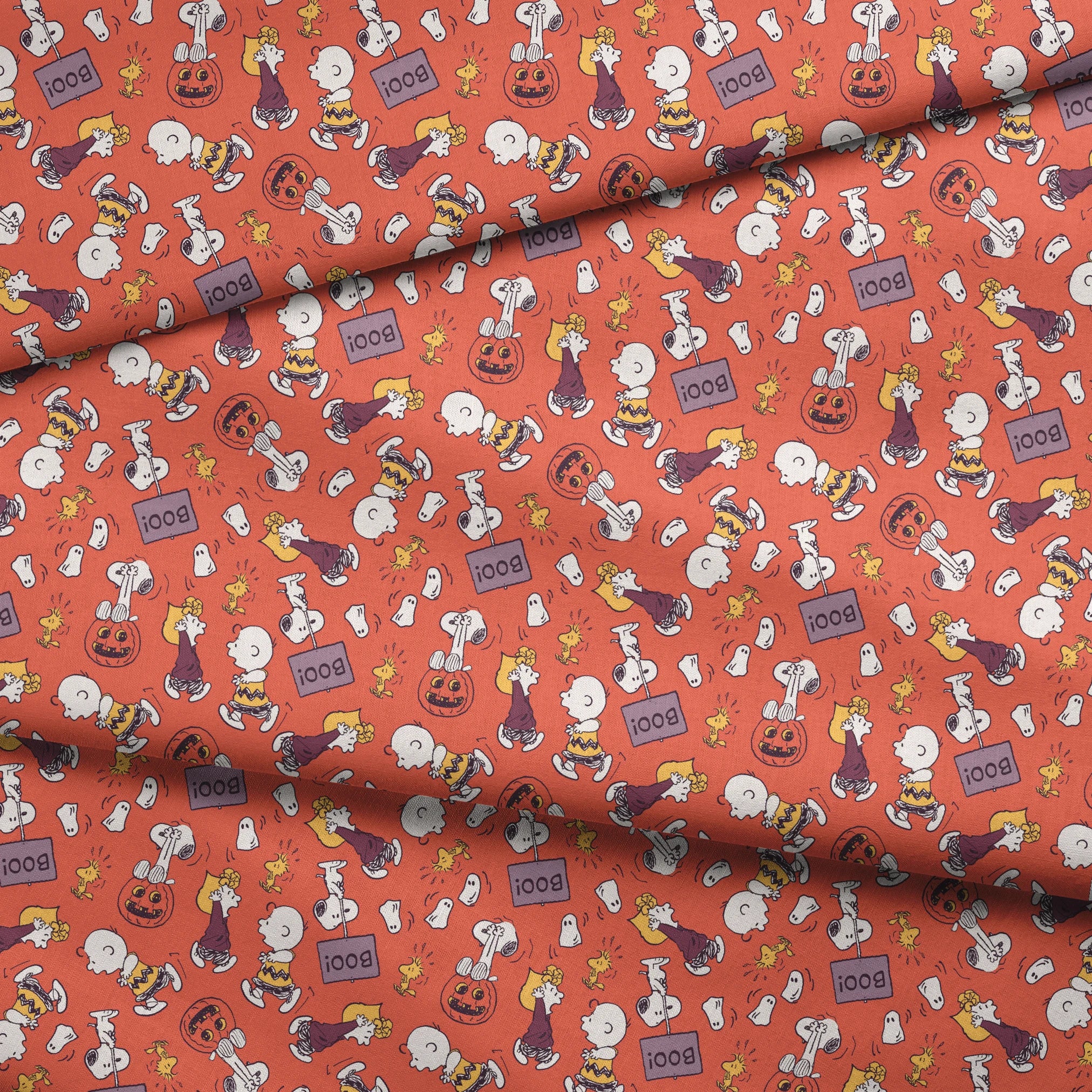 Snoopy and Woodstock Halloween pattern on orange background with pumpkins, ghosts, and "boo" text fabric fold mockup