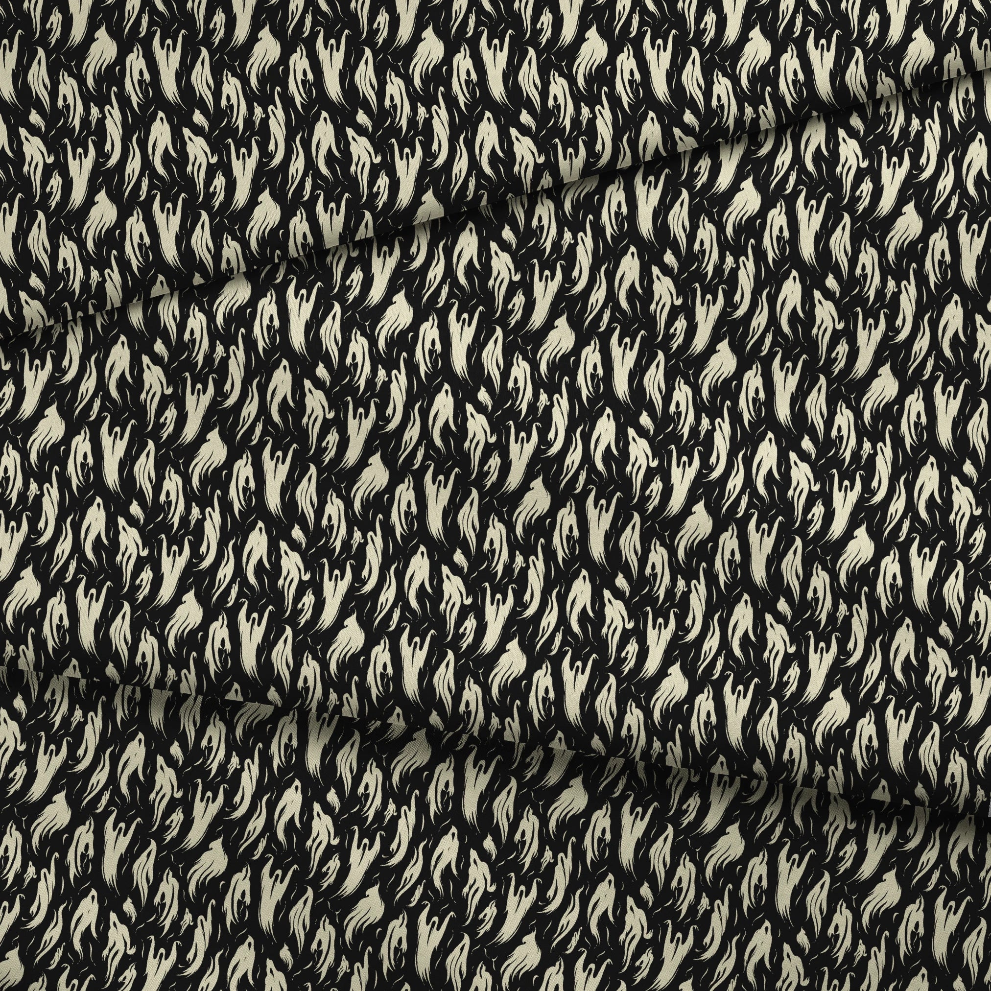 Abstract ghost-like shapes in pale cream swirling against a black background in a repeating pattern fabric fold mockup