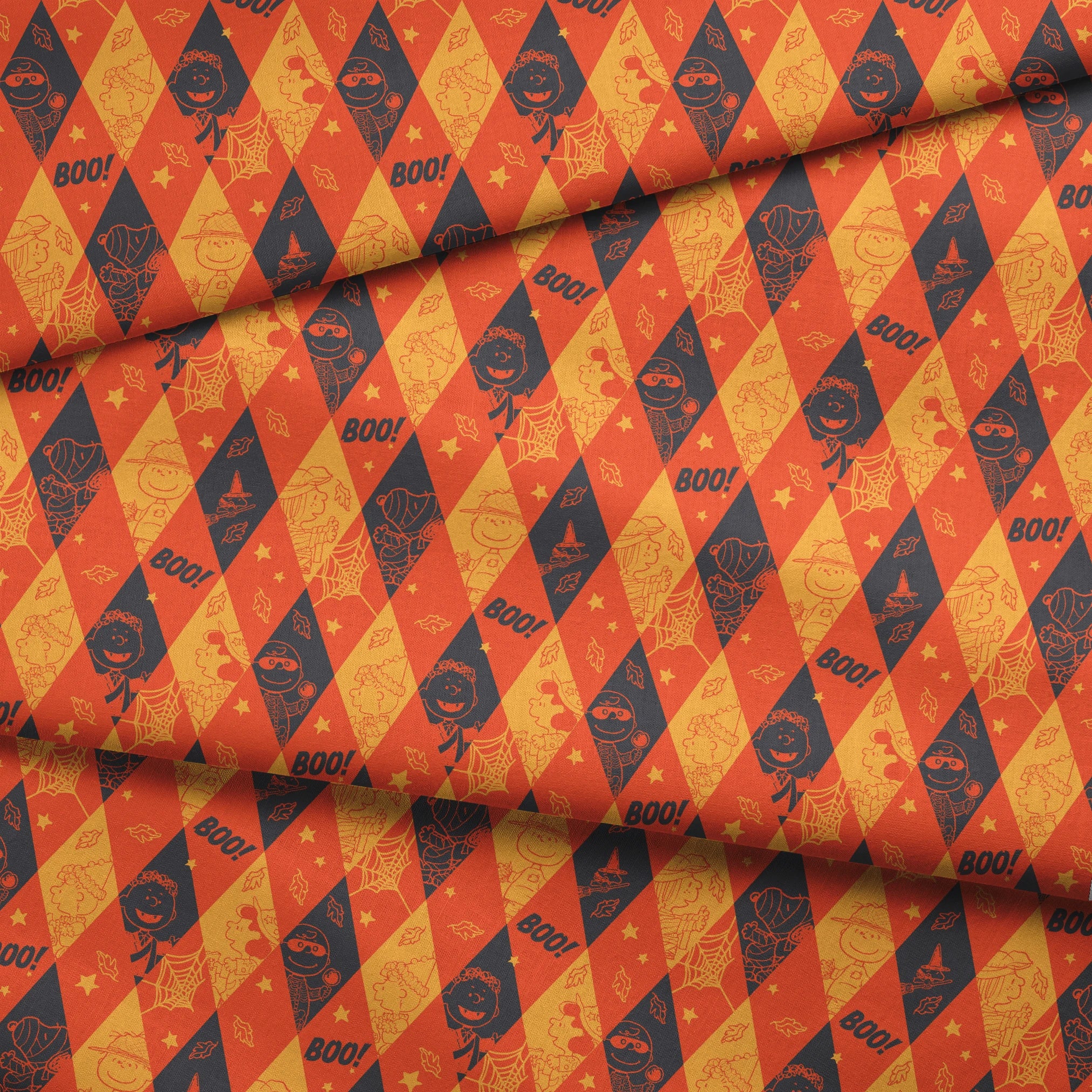 Peanuts Halloween pattern with diamond shapes in orange, yellow, and black featuring Peanuts characters in costumes, webs, "BOO!" text, and seasonal decorations fabric fold mockup