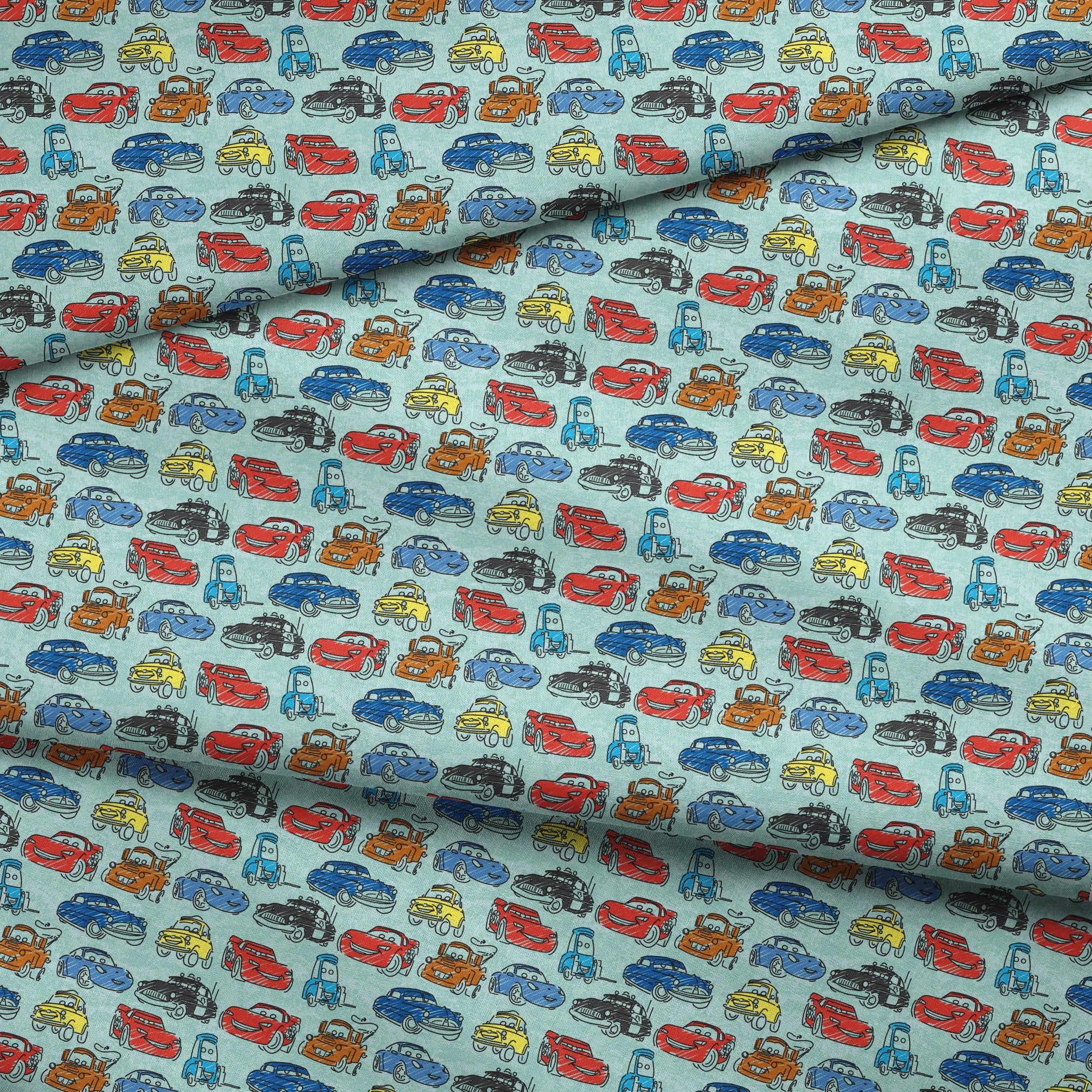 Colorful cartoon cars pattern including red racecars, blue sedans, yellow coupes, and tow trucks on light blue background fabric fold mockup