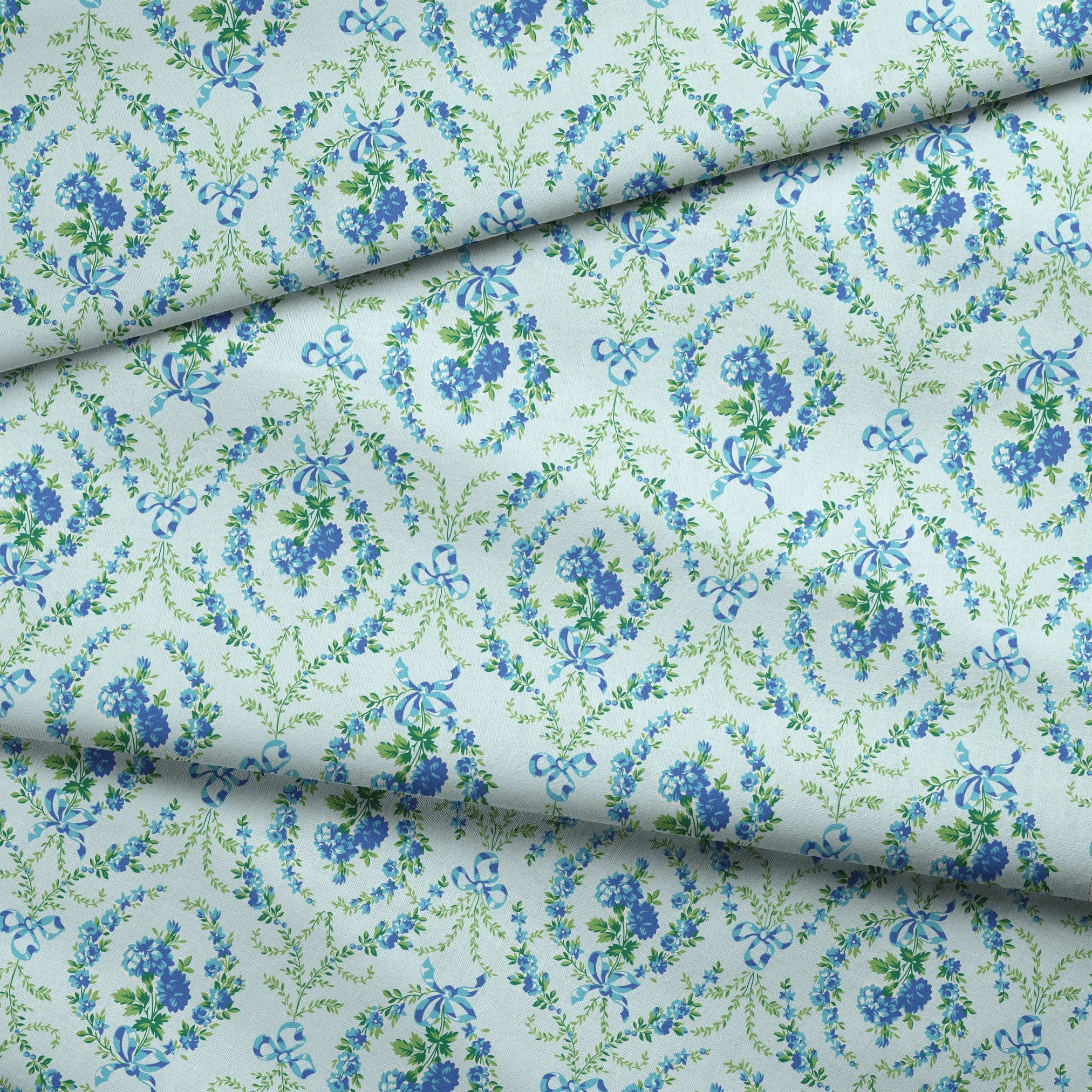 Blue floral pattern with diamond lattice design featuring delicate ribbons and green foliage on light background fabric fold mockup