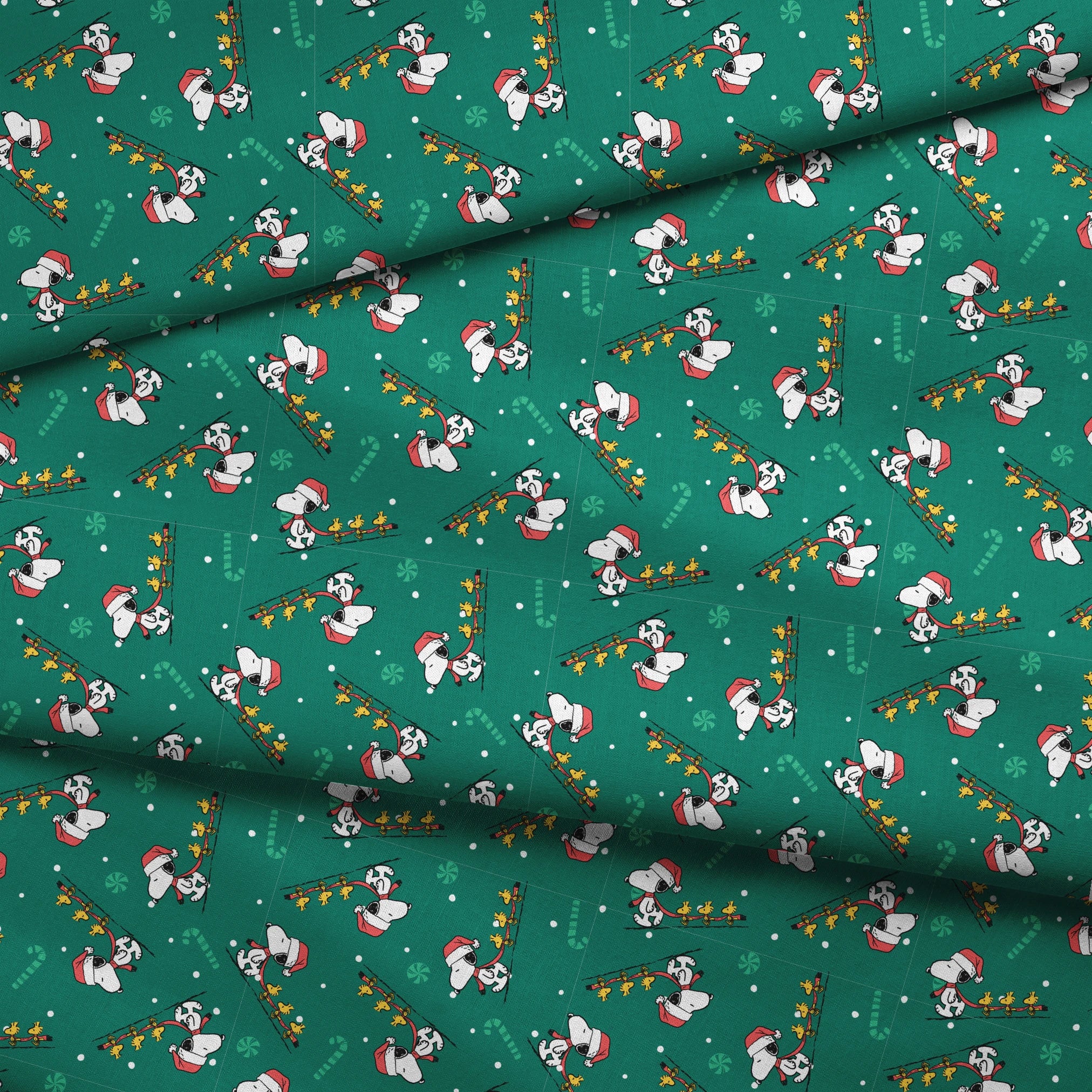 Holiday pattern with Snoopy in Santa hats pulling sleds of stars on green background with candy canes and snowflakes fabric fold mockup