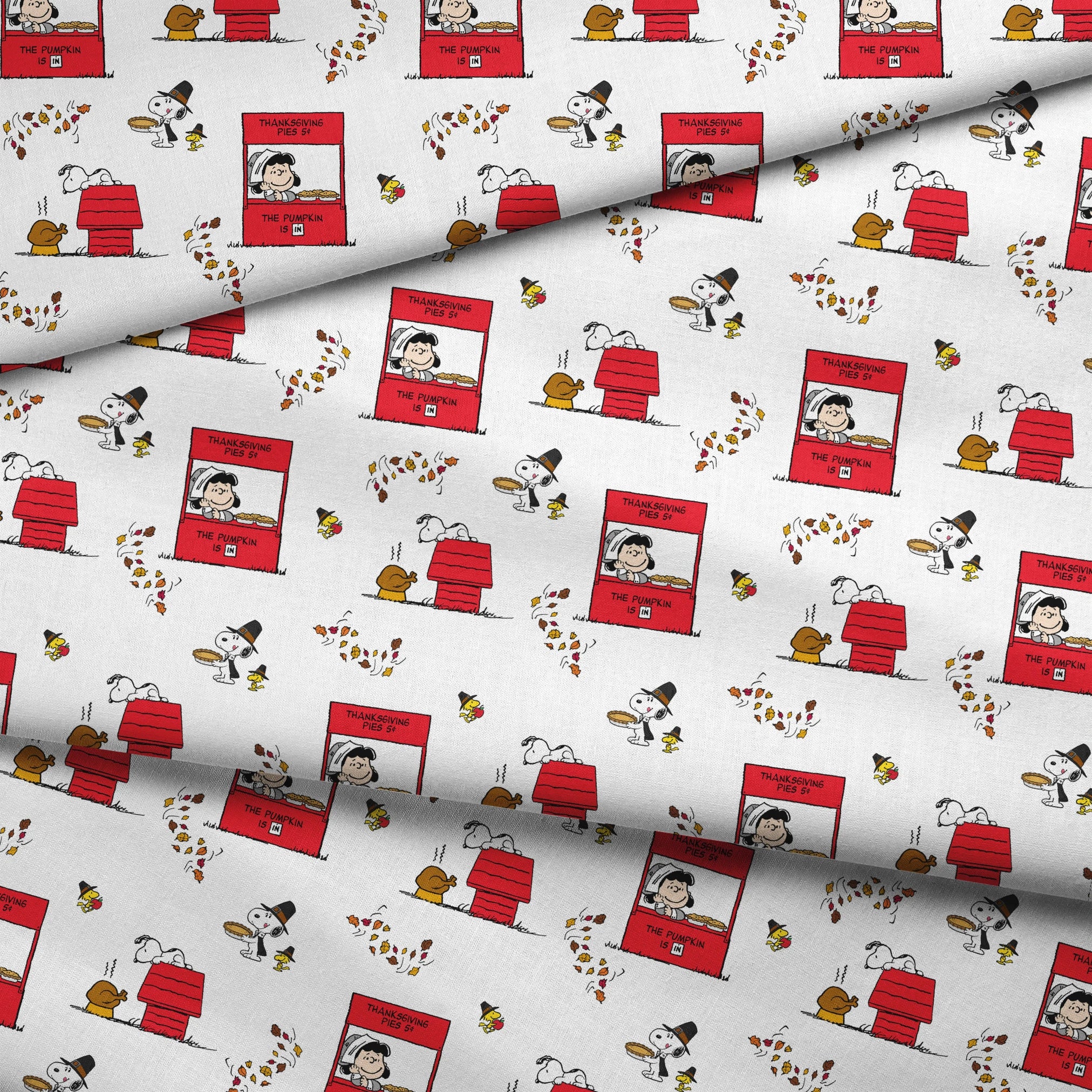 Peanuts Thanksgiving pattern with Snoopy, red booths, doghouses, and falling autumn leaves on white background fabric fold mockup