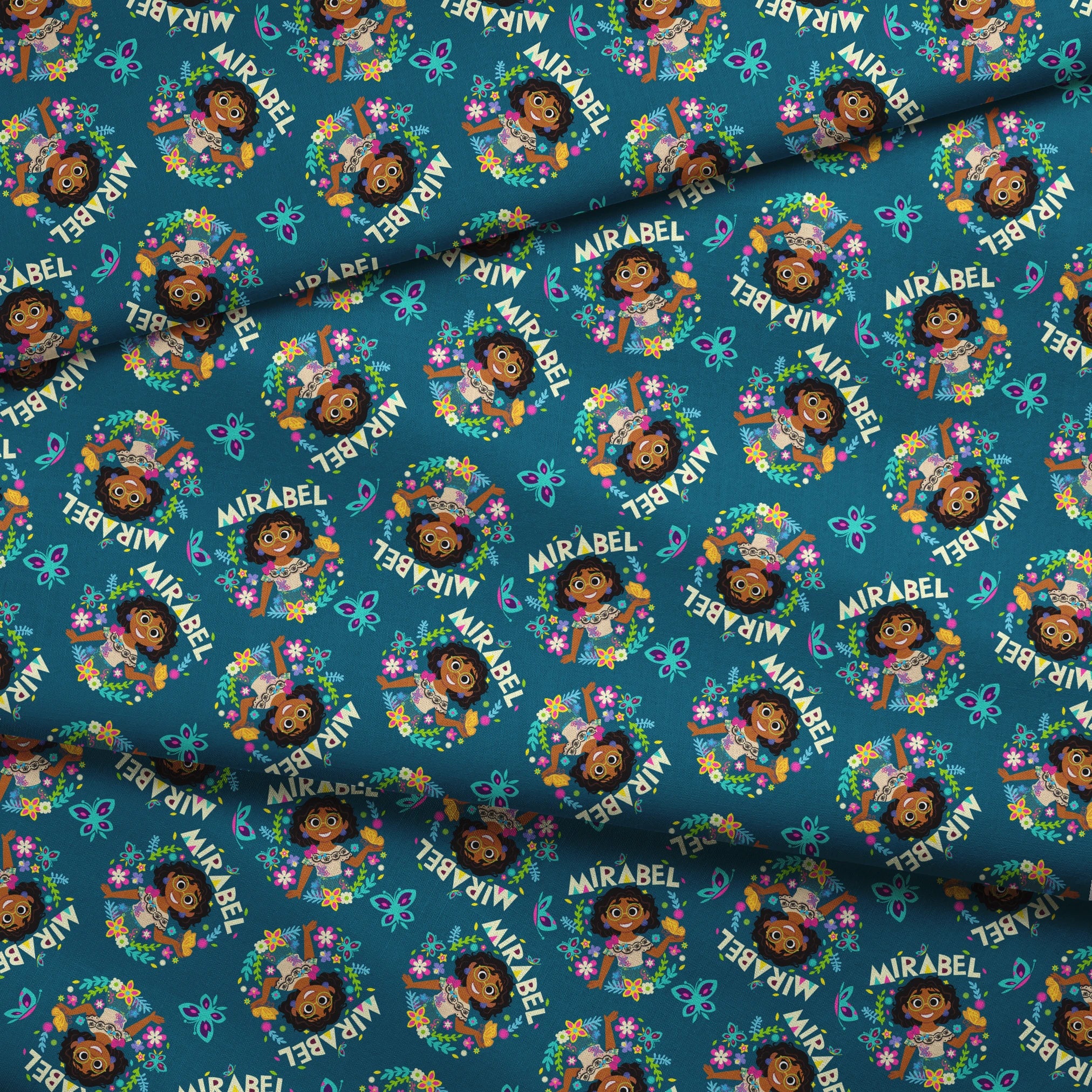 Colorful cartoon pattern on teal background featuring characters, butterflies, flowers, and "Mirabel" text in repeating design fabric fold mockup