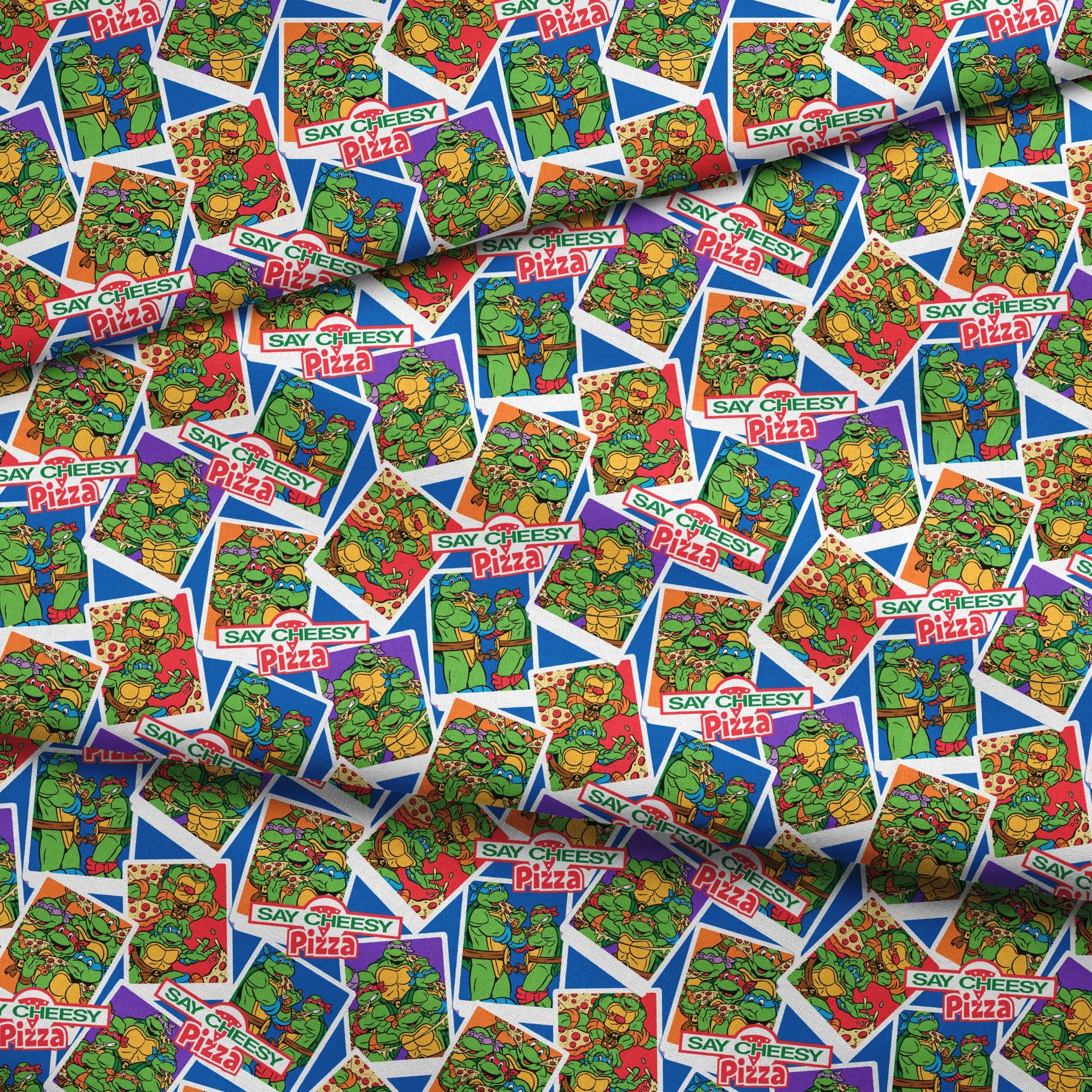 Colorful collage of Teenage Mutant Ninja Turtles cartoon characters with "Say Cheesy Pizza" text on vibrant background fabric fold mockup