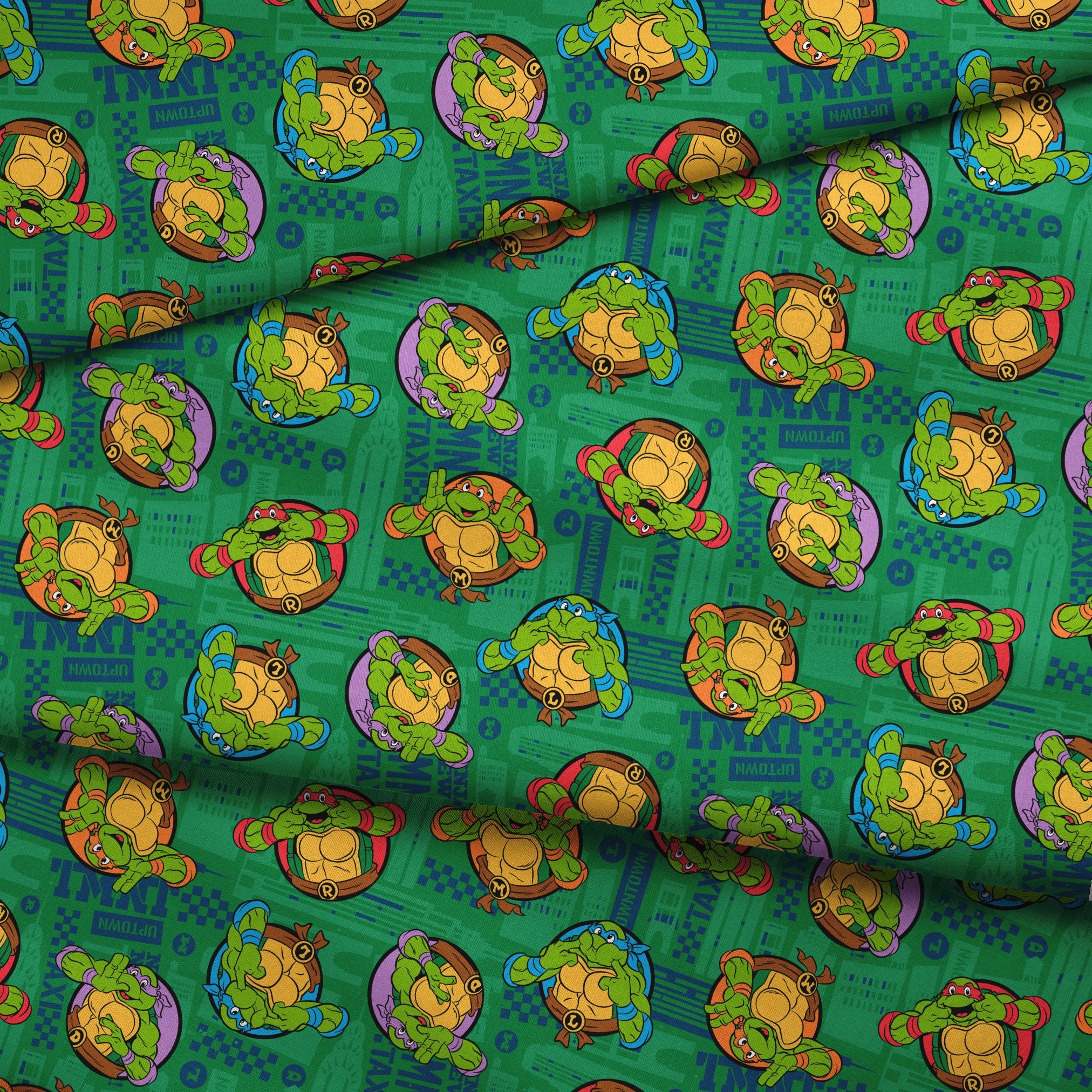 Teenage Mutant Ninja Turtles cartoon characters on green patterned background fabric fold mockup