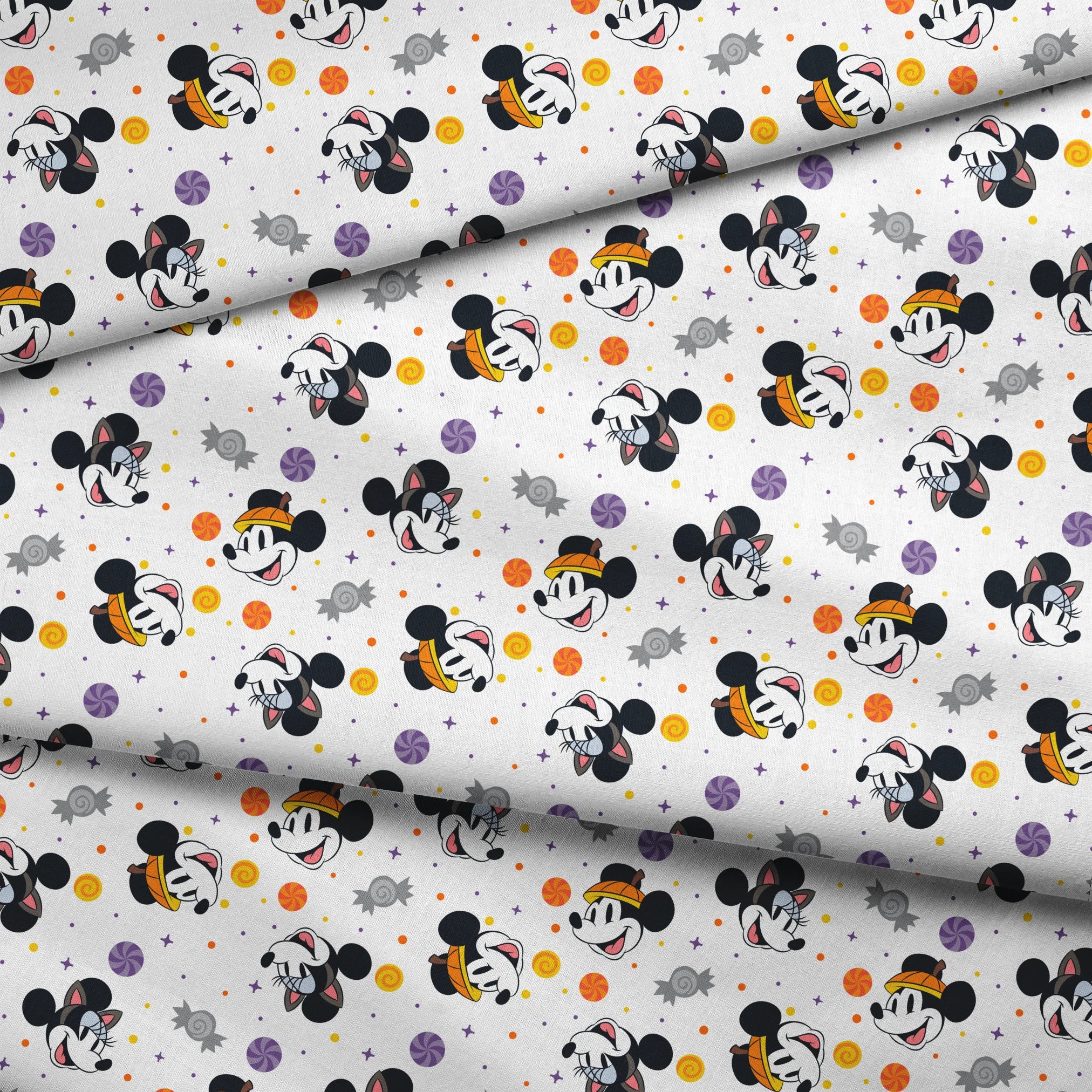 Mickey and Minnie Mouse cartoon heads scattered with wrapped candies and colorful dots on white background fabric fold mockup