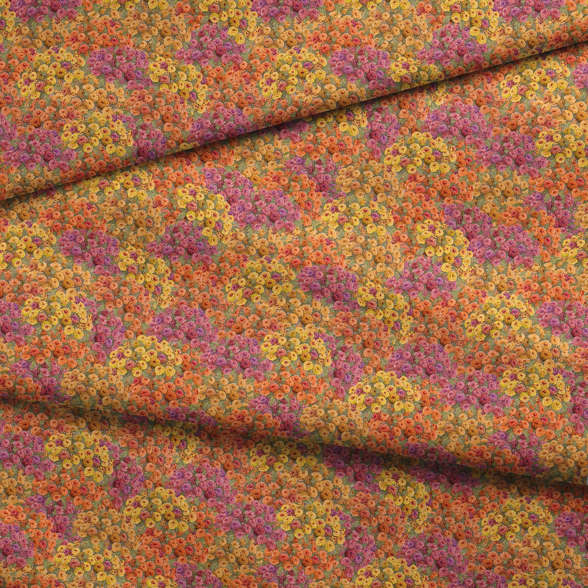 Dense floral fabric featuring orange, gold, pink, and plum zinnias in a packed all-over pattern by Nicole Tamarin. fabric fold mockup
