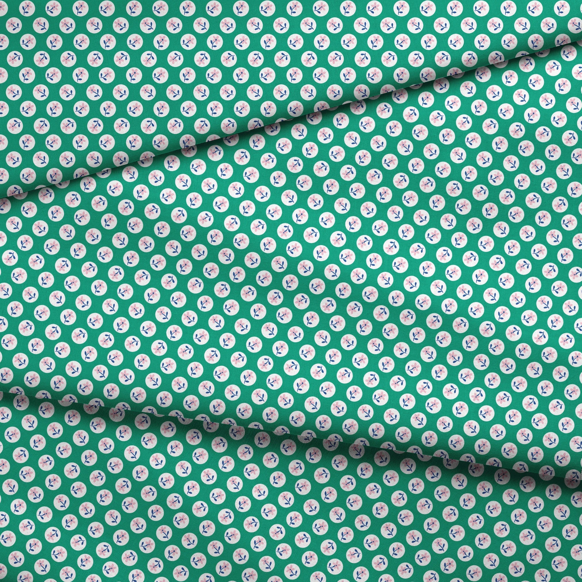 Pink flower motifs with blue stems on white circles against a green background fabric fold mockup