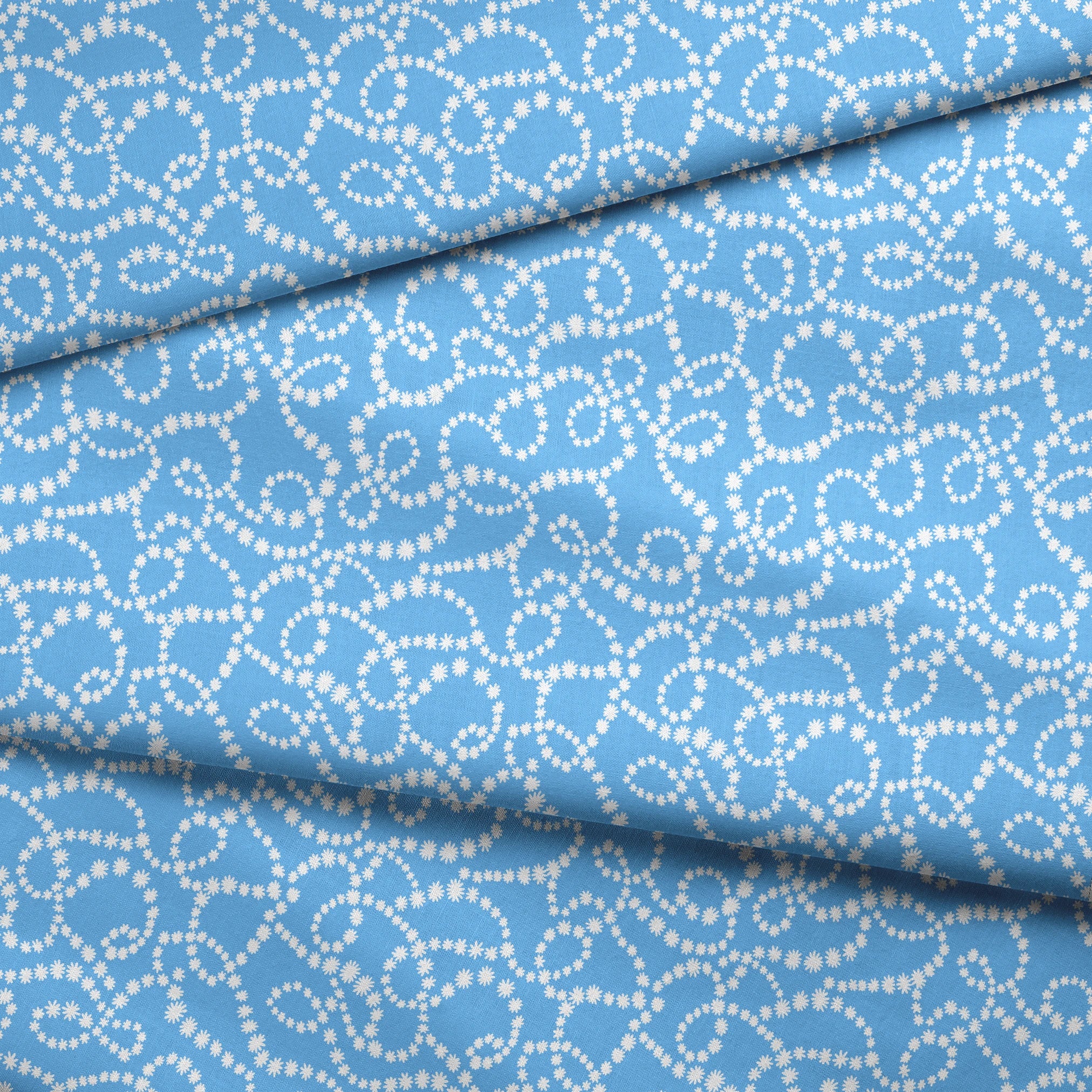 Sky blue background with swirling white dotted pattern resembling beaded strings or pearls arranged in curving lines fabric fold mockup
