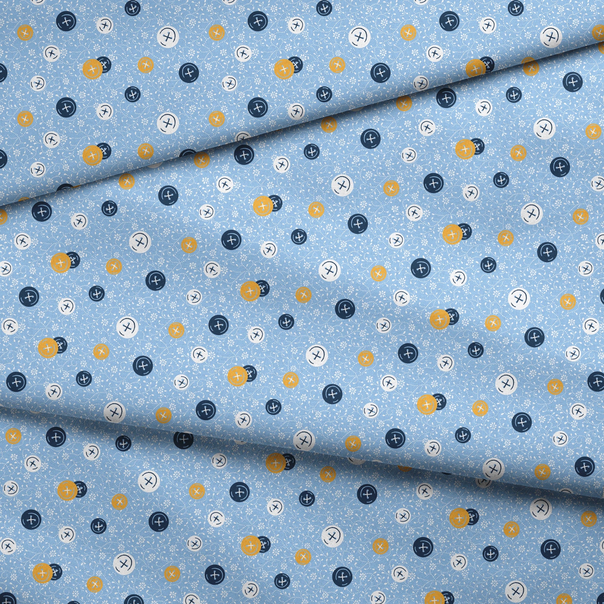 Blue background with scattered circular buttons in white, navy, and gold, each featuring cross designs, on a floral pattern. fabric fold mockup