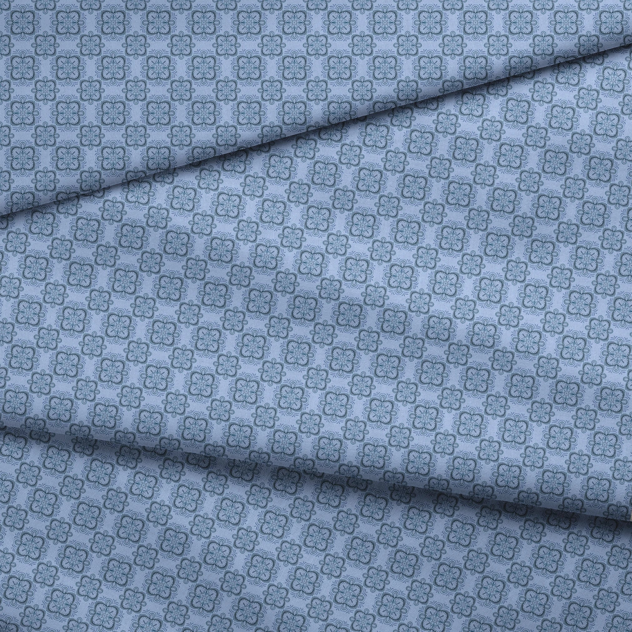 Symmetrical floral mandala pattern in layered blue tones with hand-drawn botanical details, designed by Nicole Tamarin. fabric fold mockup