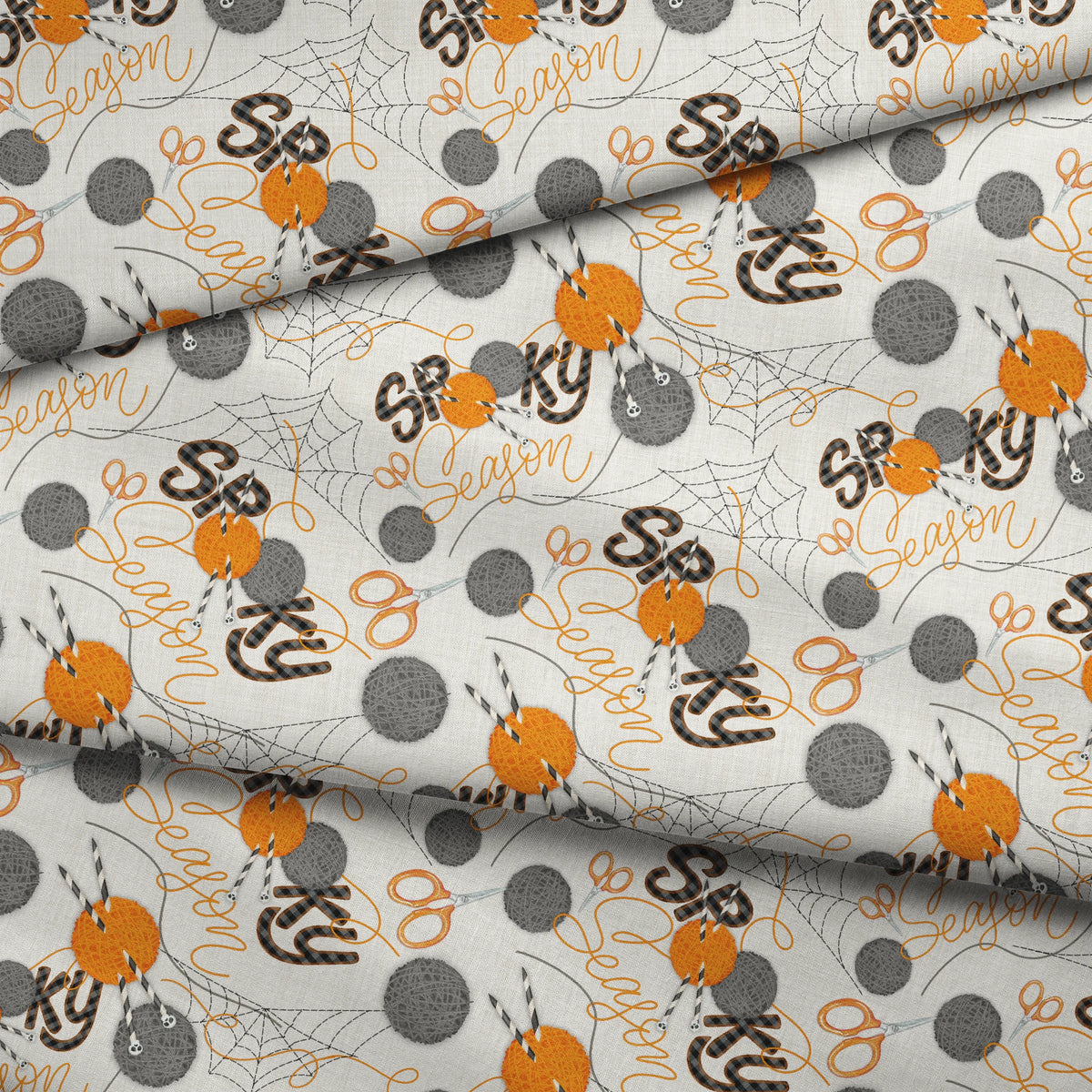 Halloween design by Nicole Tamarin featuring orange and gray yarn balls, scissors, spiderwebs, and “Spooky Season” lettering on a cream background. fabric fold mockup