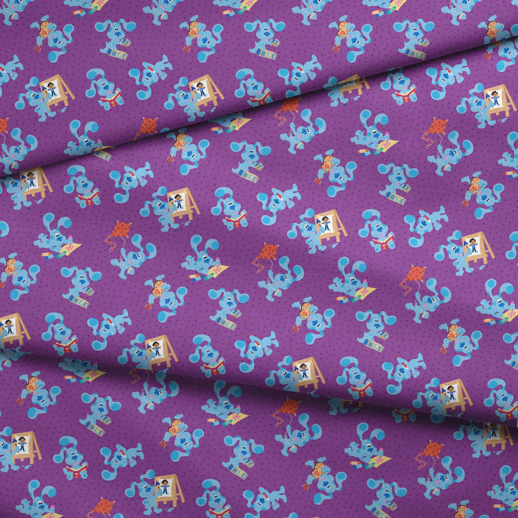 Blue cartoon dog characters on purple polka dot background with toys and alphabet blocks pattern fabric fold mockup