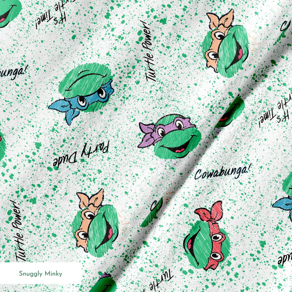 Pattern of Teenage Mutant Ninja Turtles with colorful masks on speckled green background with phrases like "Turtle Power! springs minky texture