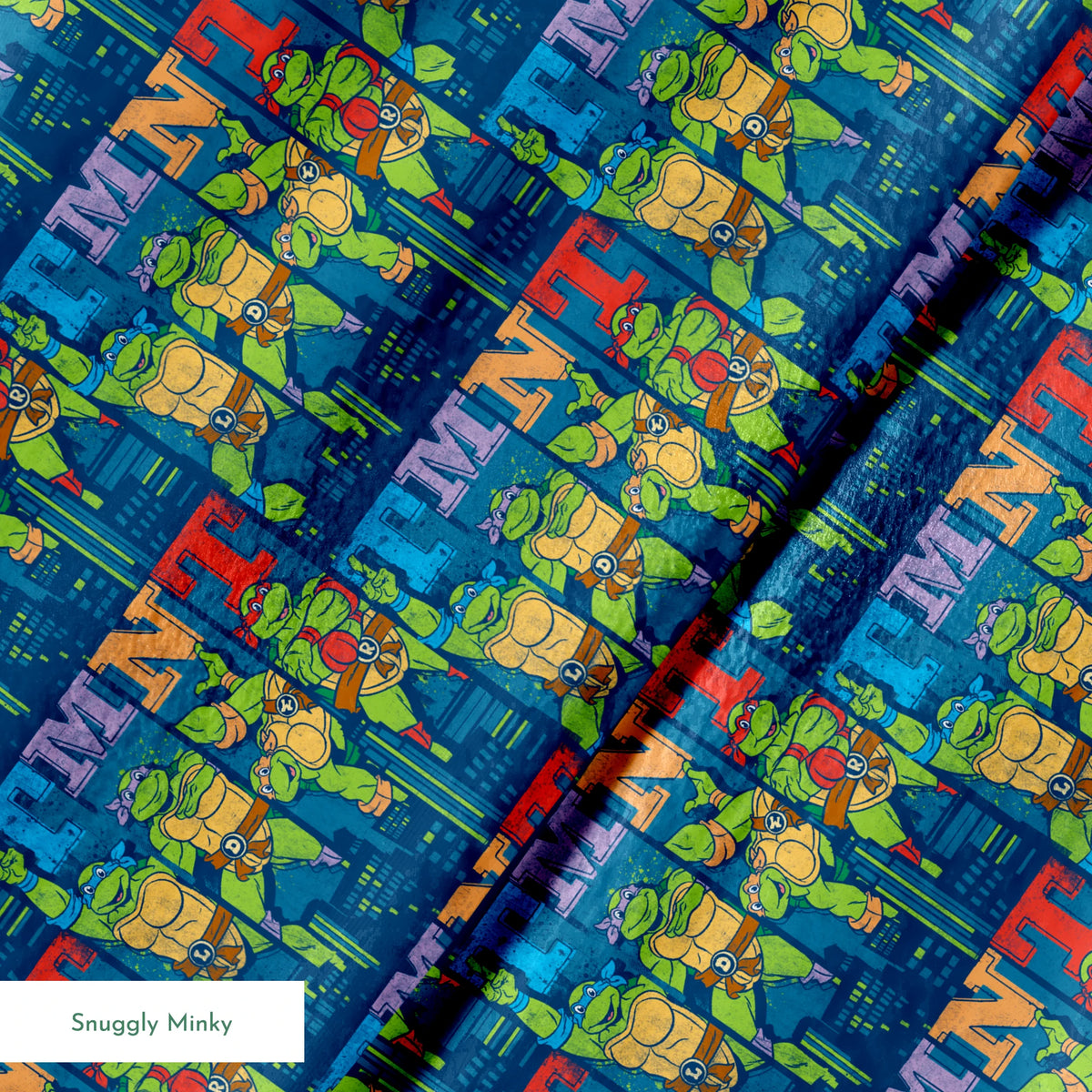 Colorful Teenage Mutant Ninja Turtles cartoon pattern with characters and "TMNT" text on blue cityscape background springs minky texture