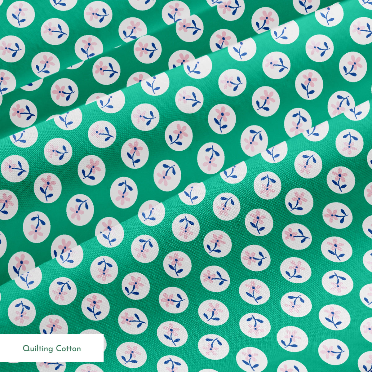 Pink flower motifs with blue stems on white circles against a green background springs quiltingcotton texture