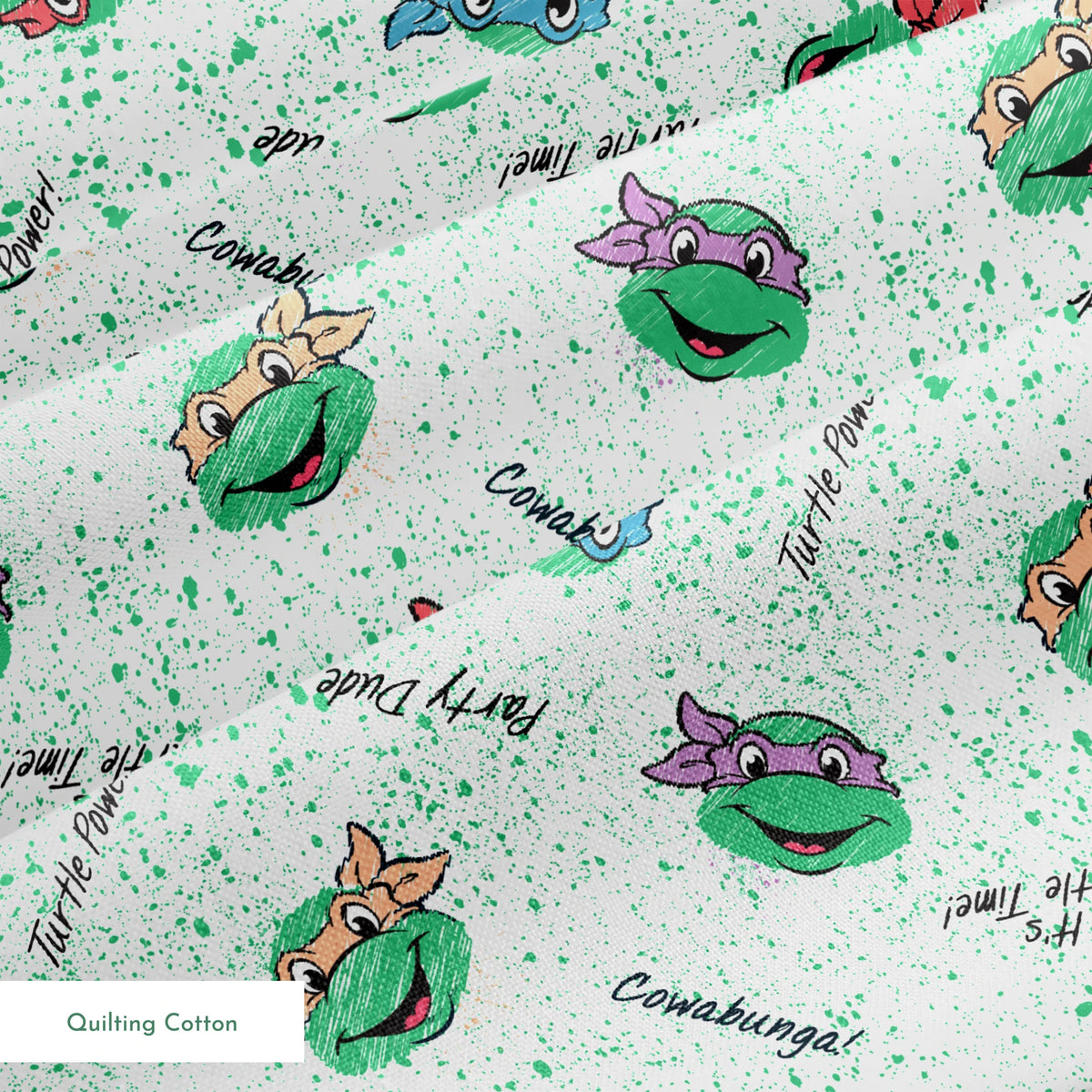 Pattern of Teenage Mutant Ninja Turtles with colorful masks on speckled green background with phrases like "Turtle Power! springs quiltingcotton texture