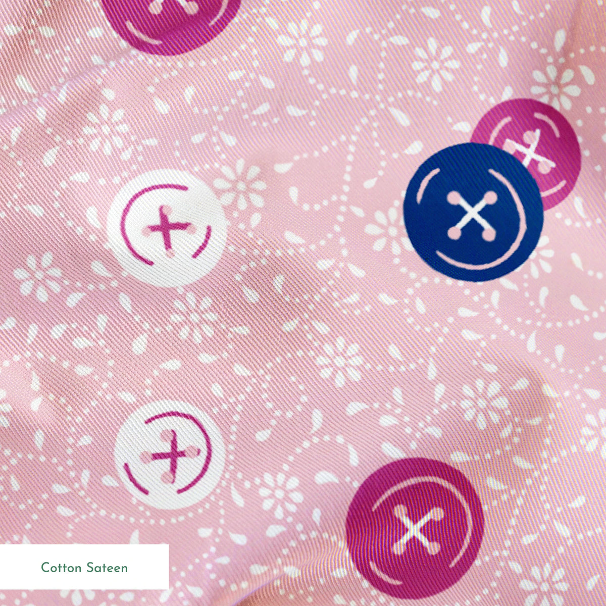 Scattered buttons in white, pink, and navy on a light pink floral background springs sateen texture