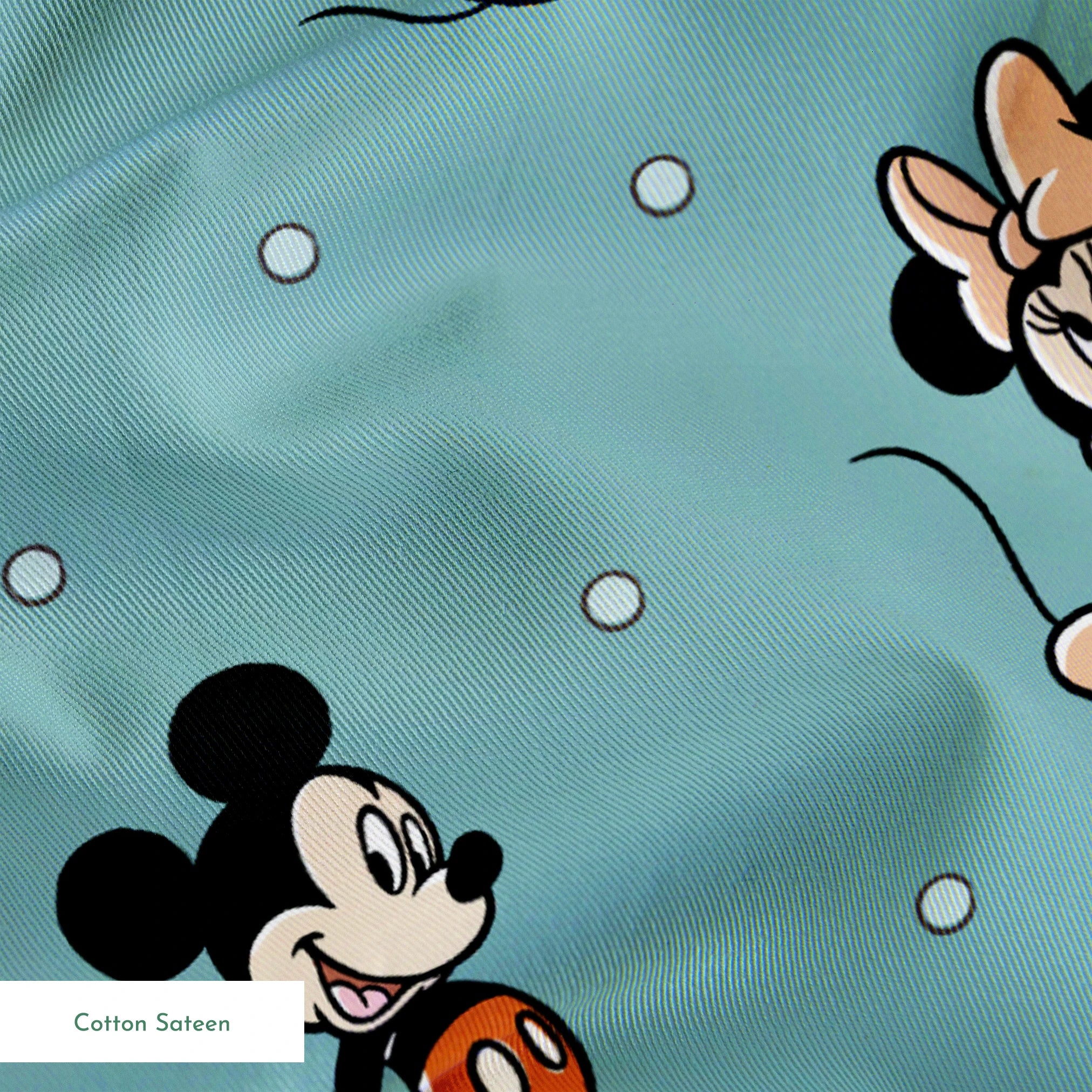 Cartoon pattern of Mickey and Minnie Mouse characters on light blue background with white dots springs sateen texture