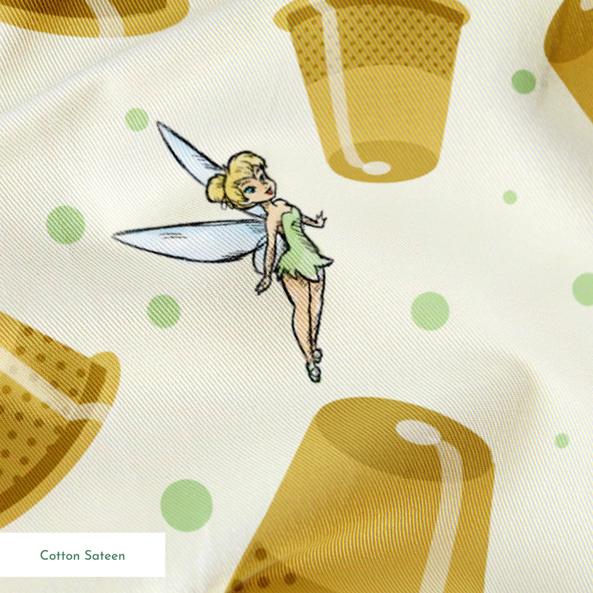 A pattern featuring Tinkerbell fairy with golden thimbles on a pale background with green dots. springs sateen texture