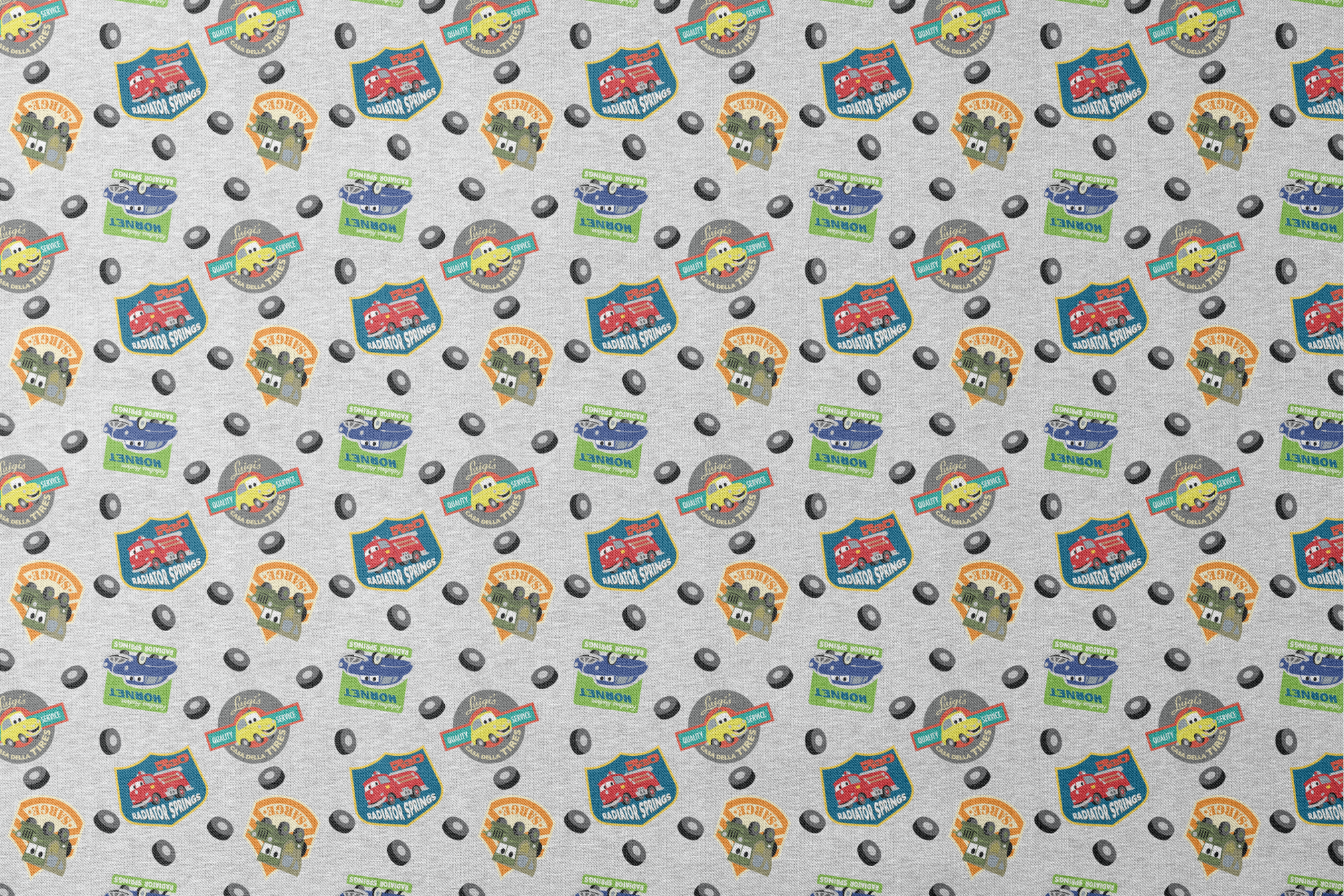 Cartoon vehicle characters on gray fabric with badges for Radiator Springs, Luigi's, and Sarge's designs flat mockup
