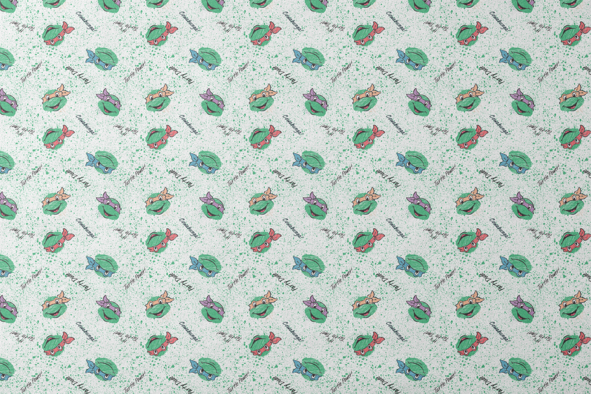 Pattern of Teenage Mutant Ninja Turtles with colorful masks on speckled green background with phrases like "Turtle Power! designs flat mockup