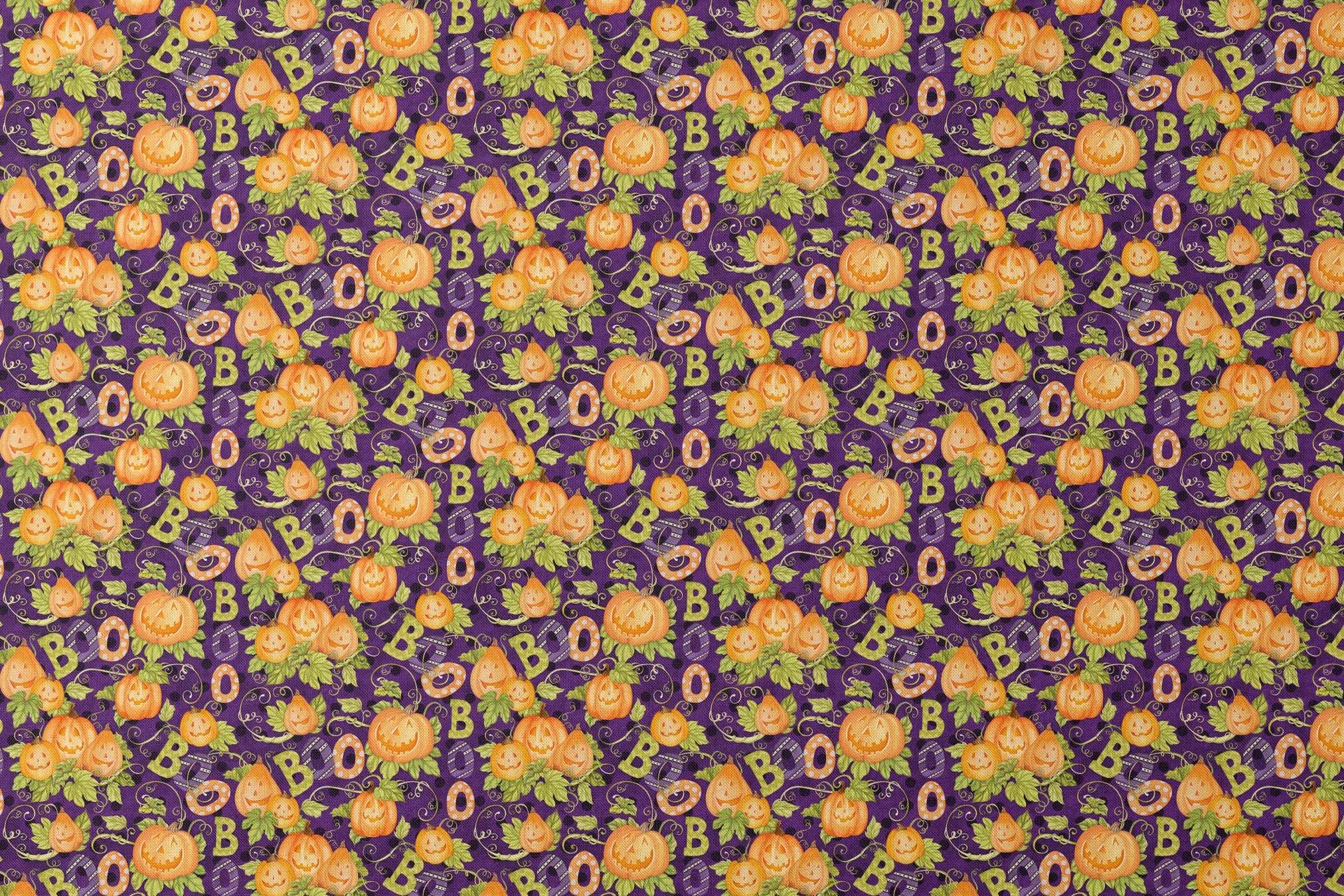 Halloween fabric by Nicole Tamarin with smiling jack-o’-lanterns, “BOO” text, vines, and leaves on a purple background. designs flat mockup
