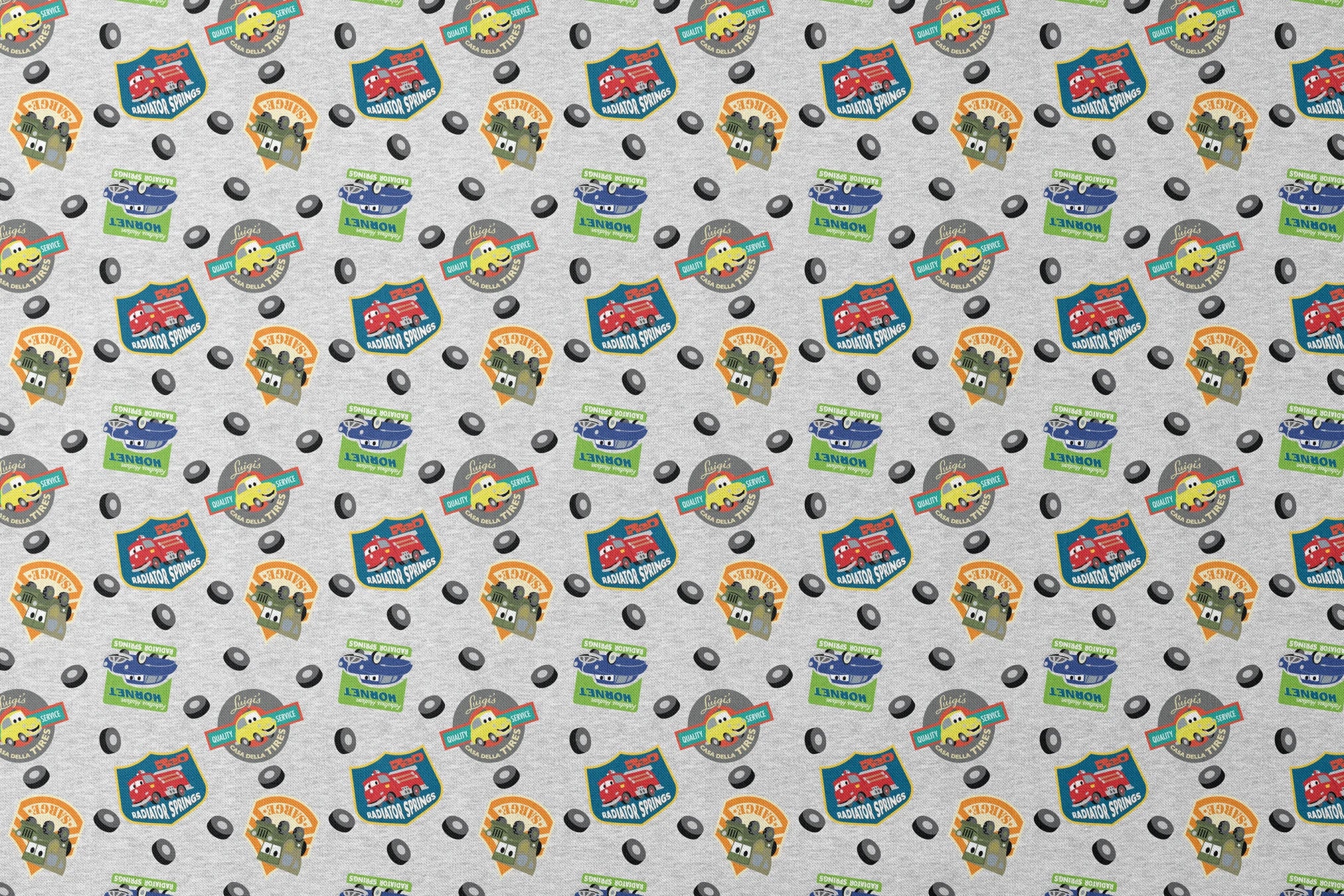 Cartoon vehicle characters on gray fabric with badges for Radiator Springs, Luigi's, and Sarge's designs flat mockup