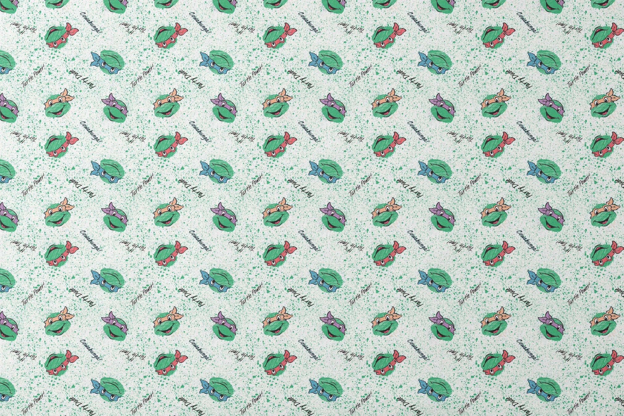 Pattern of Teenage Mutant Ninja Turtles with colorful masks on speckled green background with phrases like "Turtle Power! designs flat mockup
