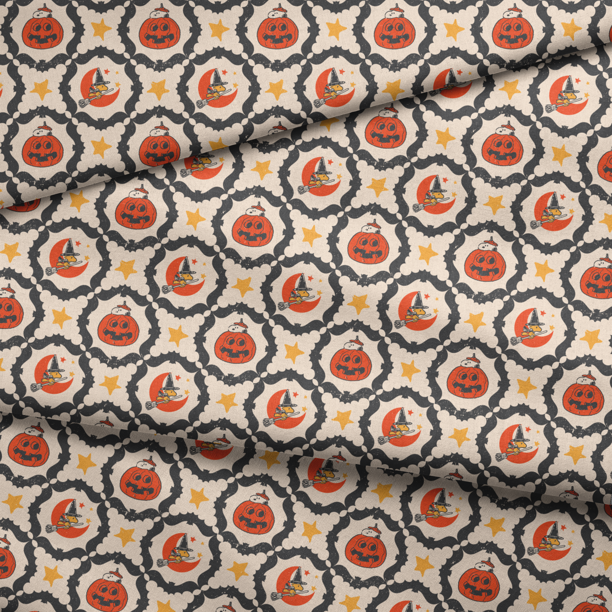 Peanuts Halloween pattern with orange jack-o'-lanterns, crescent moons with witch hats, yellow stars, and black bat borders on cream background fabric fold mockup