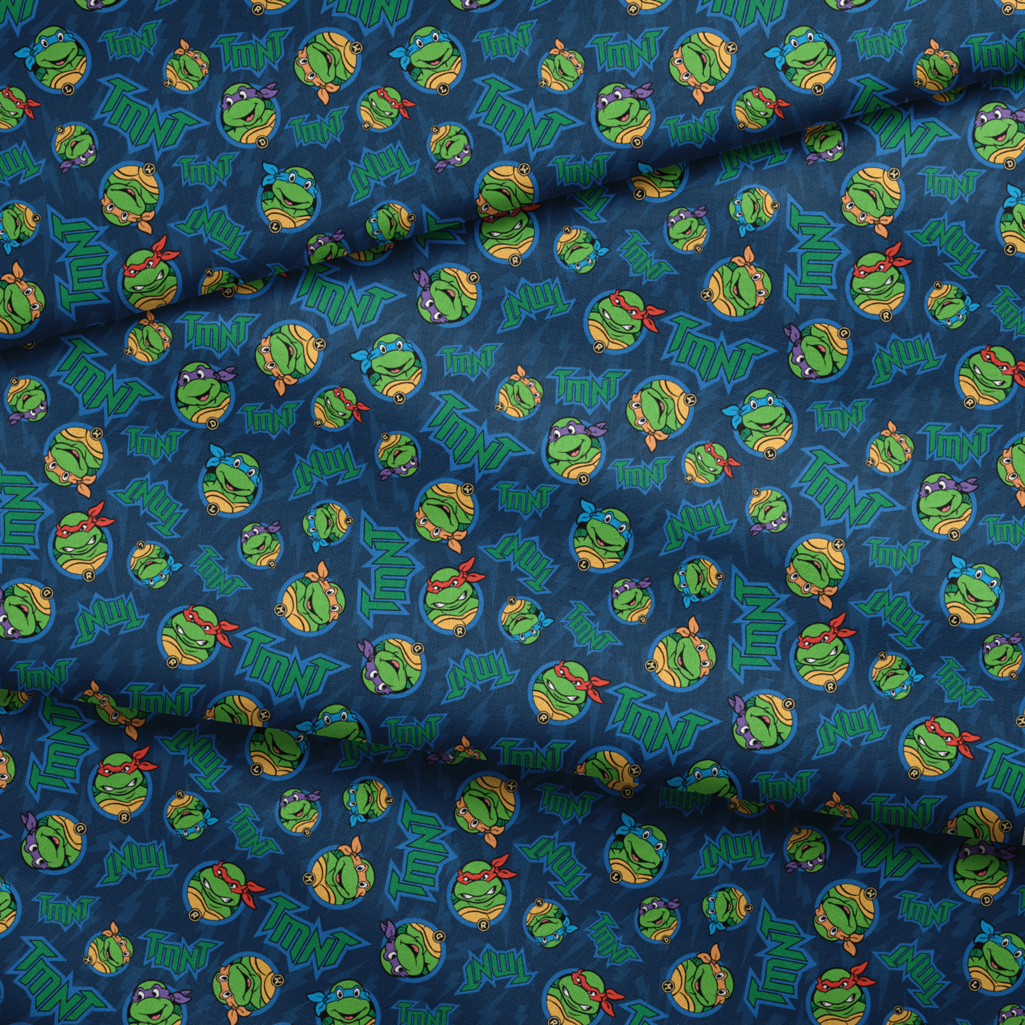 Teenage Mutant Ninja Turtles pattern with character heads and TMNT logos on blue background fabric fold mockup