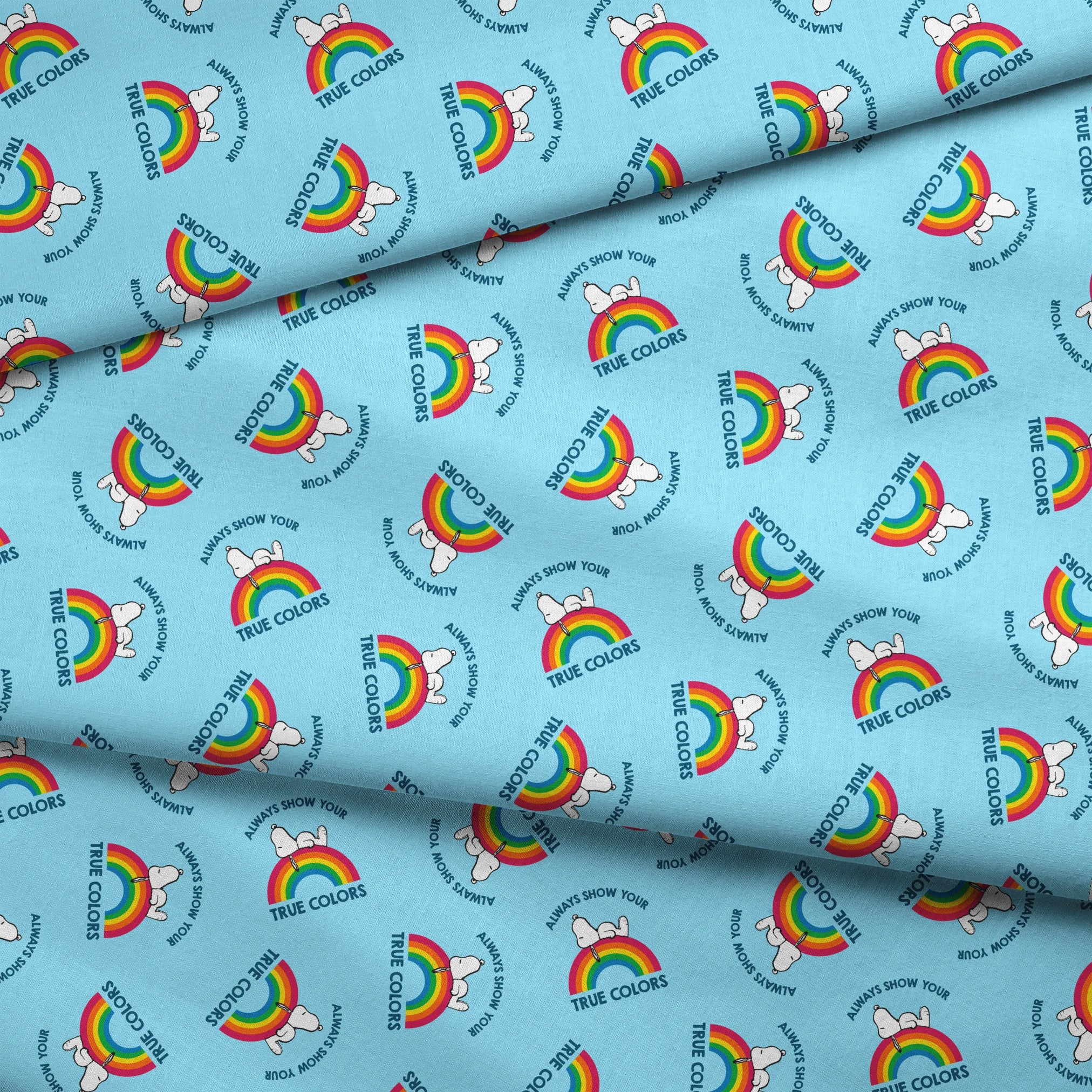Rainbow Snoopy pattern on light blue background with white clouds and "TRUE COLORS" and "ALWAYS SHOW YOUR" text repeated throughout design fabric fold mockup