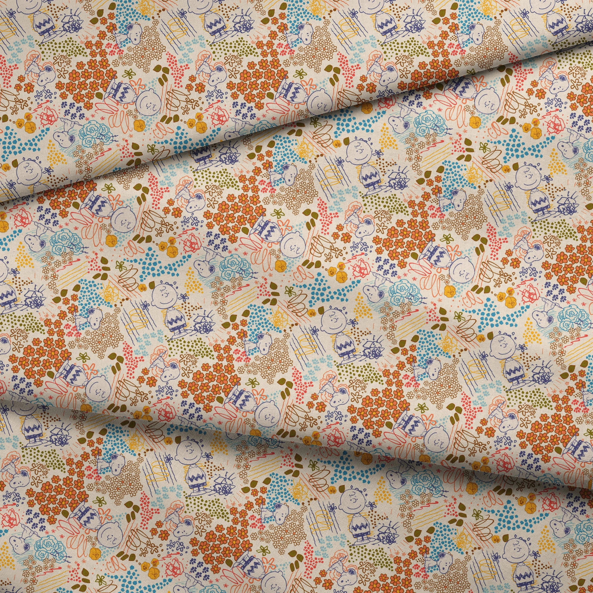 Colorful pattern with Peanuts characters sketches, floral designs, and dots in orange, blue, yellow, and green on a cream background fabric fold mockup