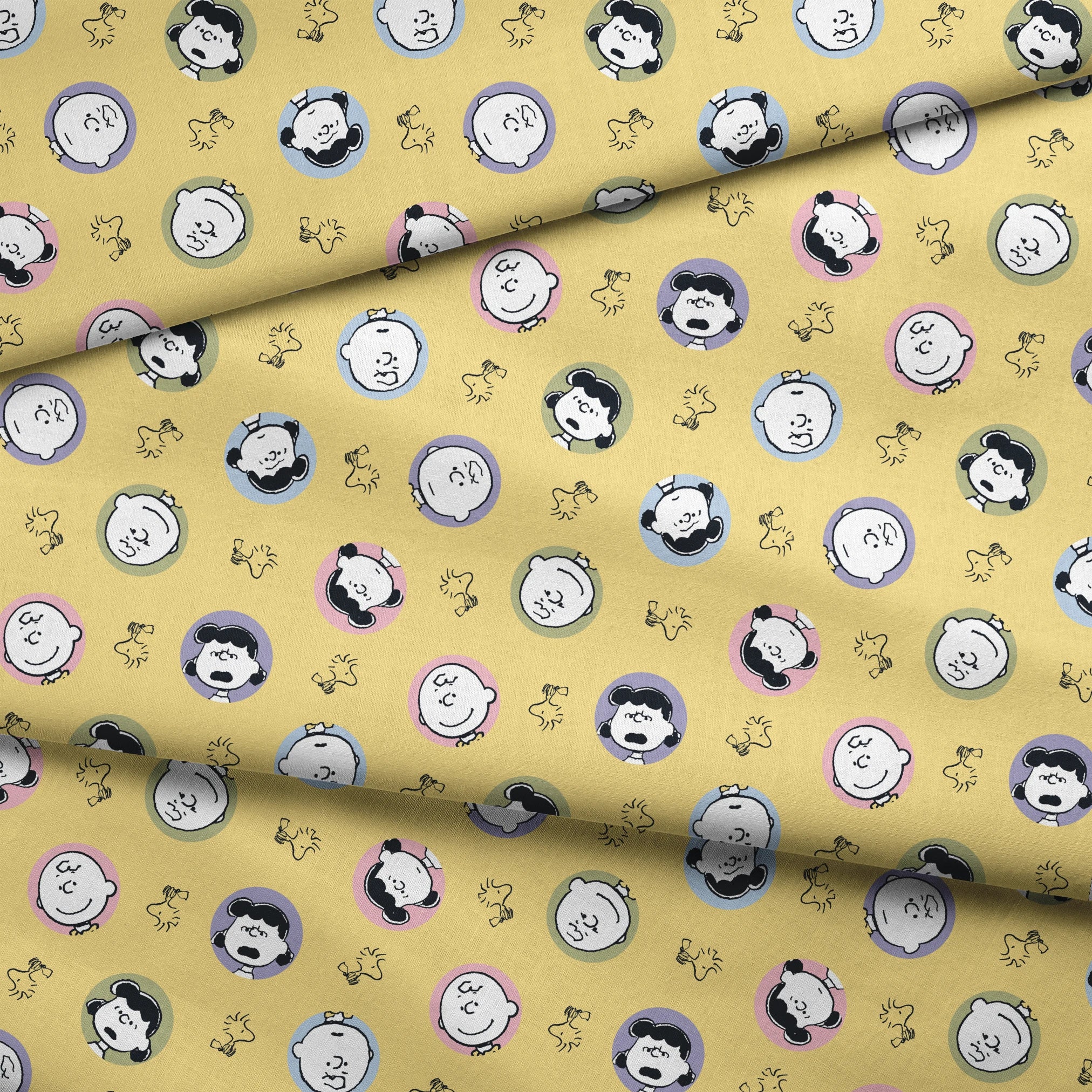 Peanuts characters pattern with Charlie Brown and friends in circular frames on yellow background with Woodstock silhouettes fabric fold mockup