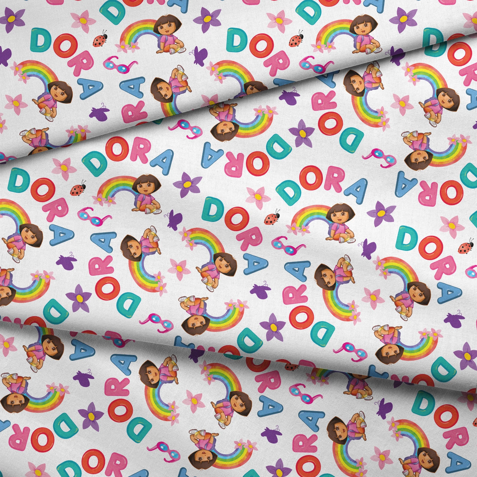 Colorful Dora pattern with rainbows, flowers, alongside scattered "DORA" letters on white background. fabric fold mockup