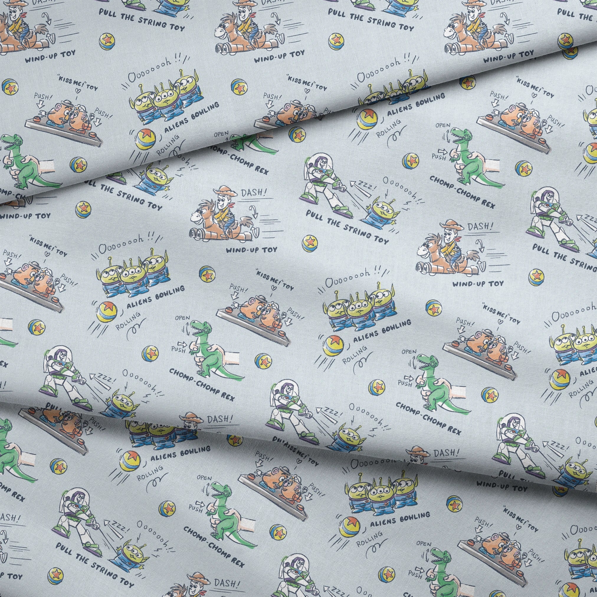 Illustrated Toy Story character designs showing wind-up, pull string, and action toys on light blue background fabric fold mockup