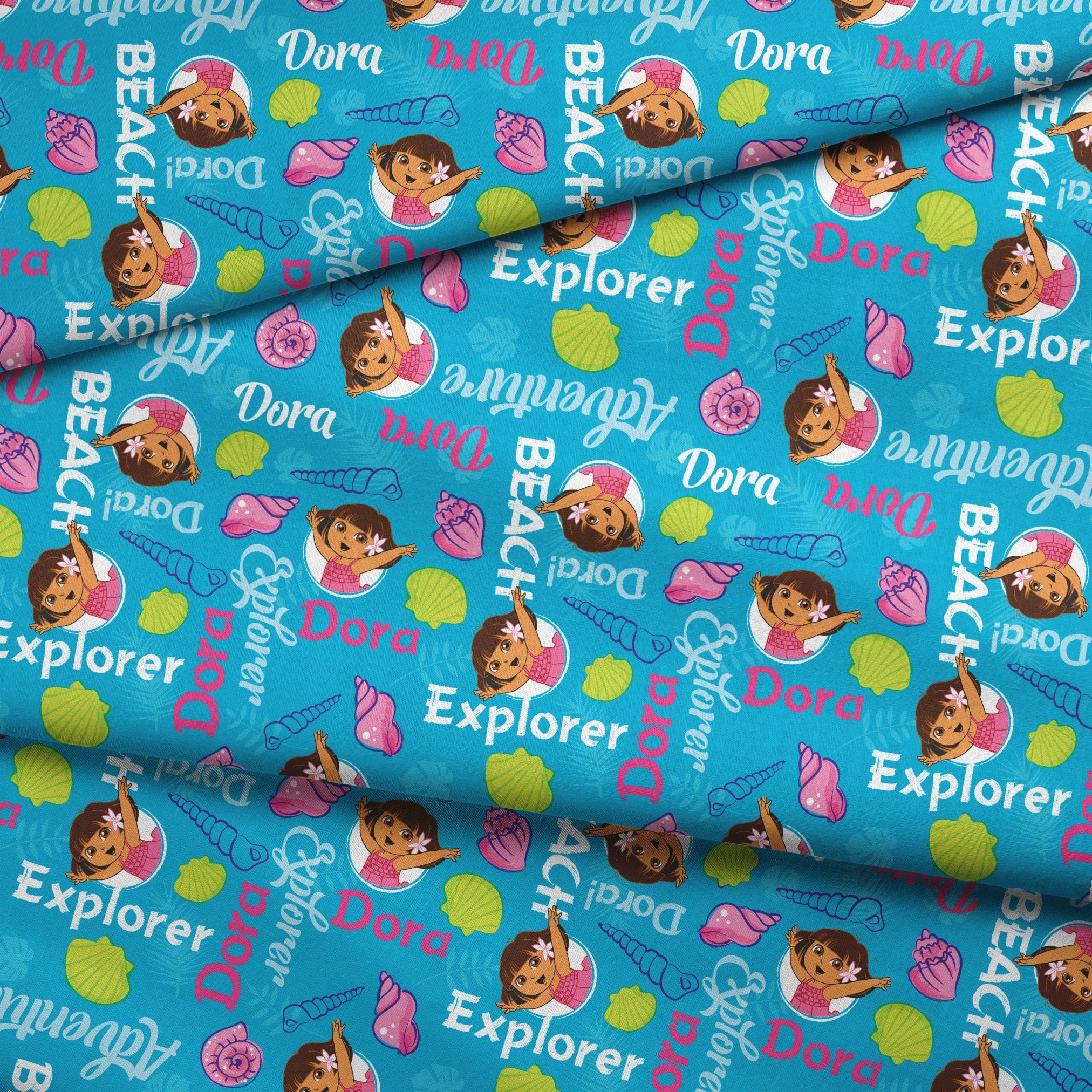 Bright blue pattern featuring Dora the Explorer cartoon character with seashells and "Beach Explorer" text fabric fold mockup